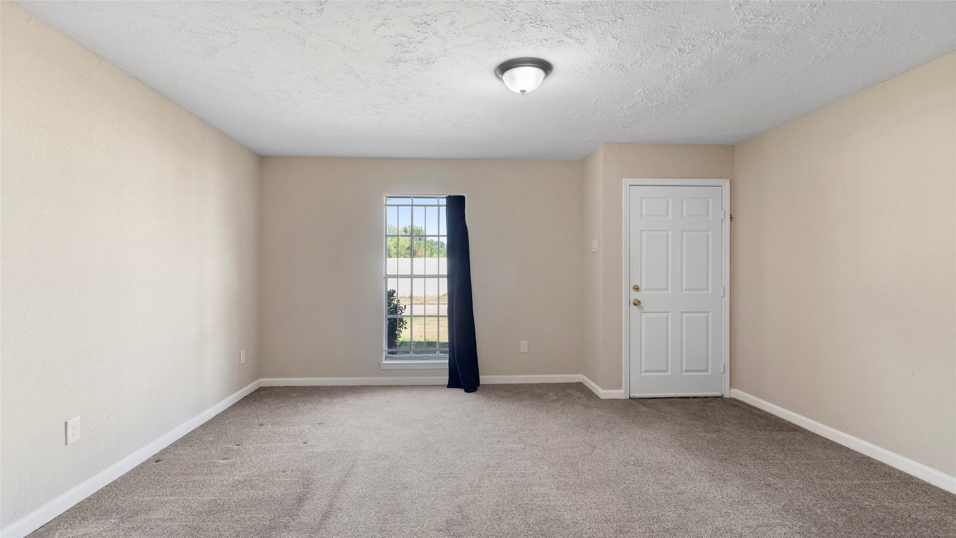 Bright front living room with a tall window and neutral colors.