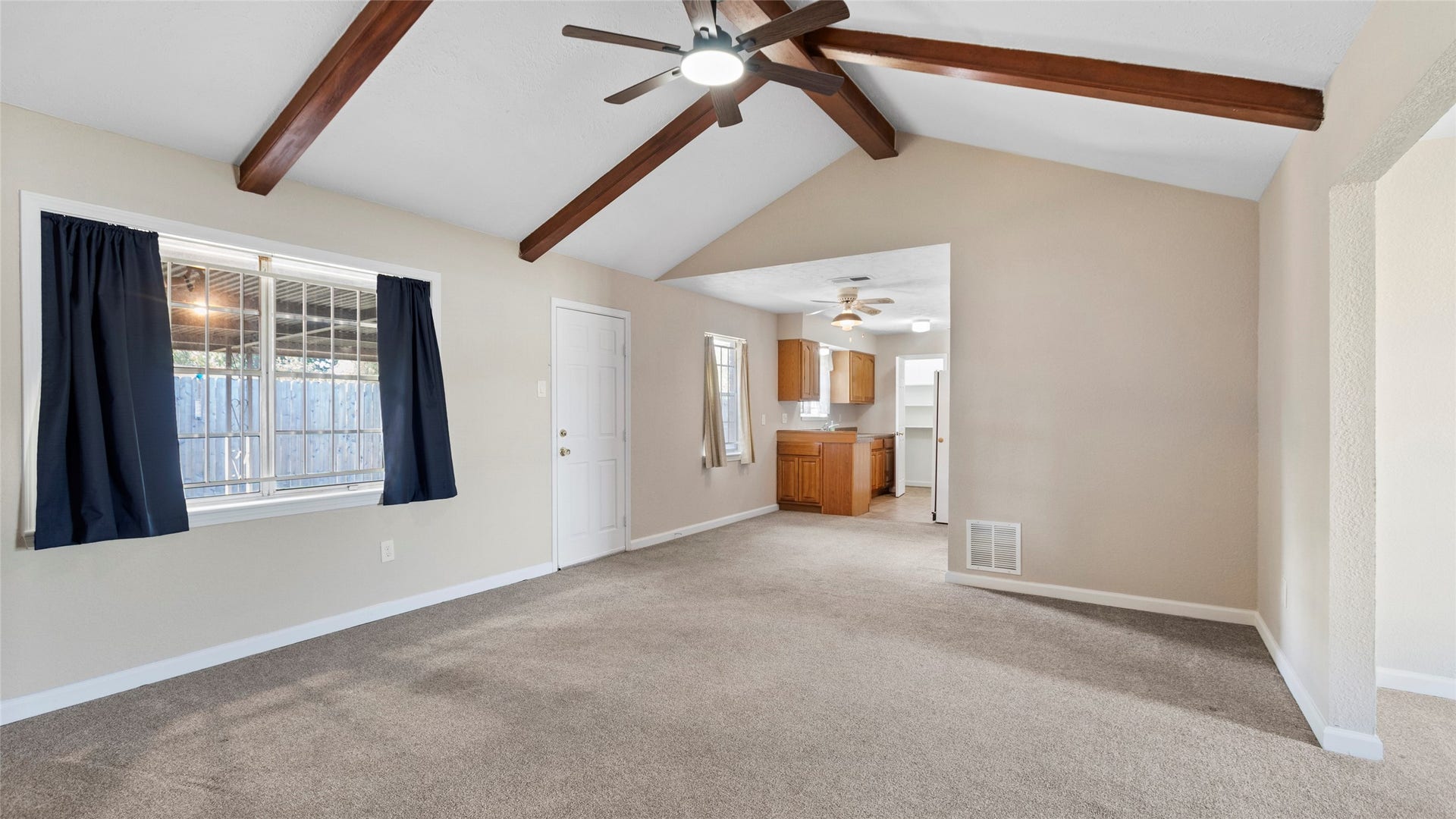 Family room featuring a vaulted ceiling, exposed beams, and access to the covered patio.