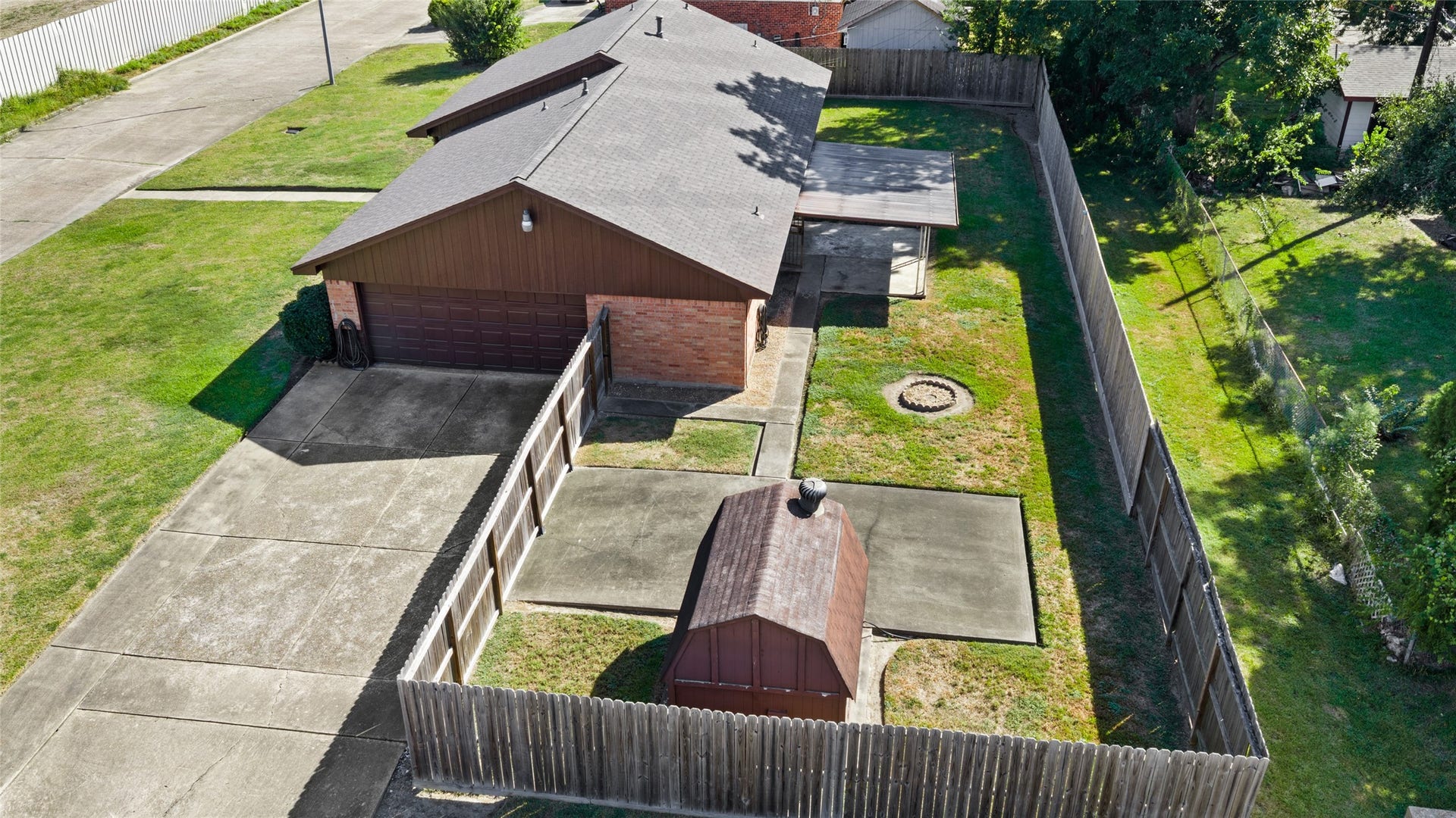 Aerial view of the fenced backyard, covered patio, and storage shed.