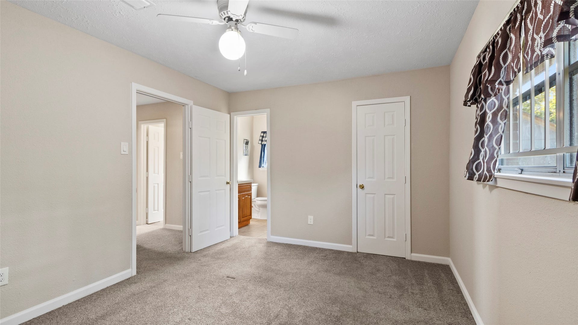 Bedroom with a ceiling fan and direct access to an updated bathroom.