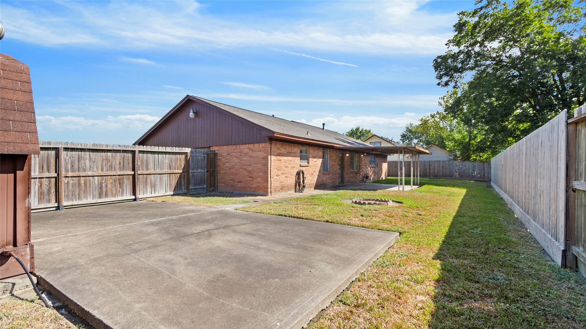 Backyard featuring a covered patio and additional concrete pad.