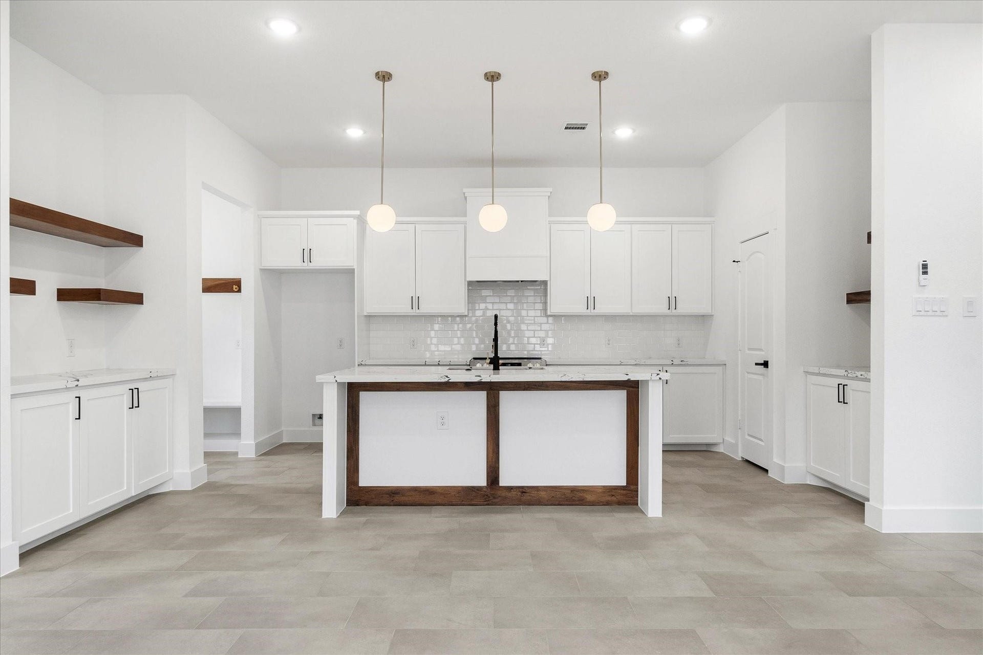 Three pendant lights illuminate your large island with additional seating, and the wood accents add a touch of warmth to this elegant space. (Photos of a previously built home with the same floor plan. For illustrative purposes only; final finishes may vary.