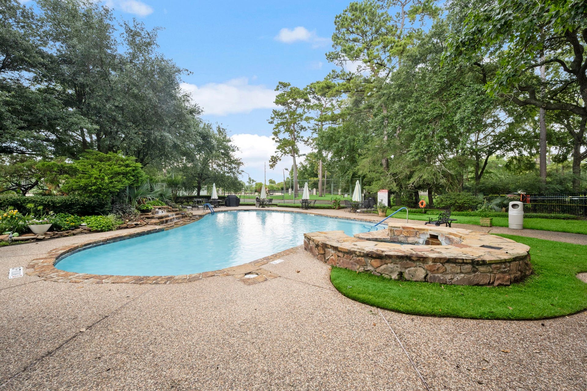 14655 Champion Forest Drive, #1201, Houston, TX 77069 The pool & spa area is nestled among mature trees and lush landscaping, offering a refreshing retreat from the summer sun. Just beyond, enjoy access to a private park and well-maintained tennis courtsperfect for both relaxation and recreation.