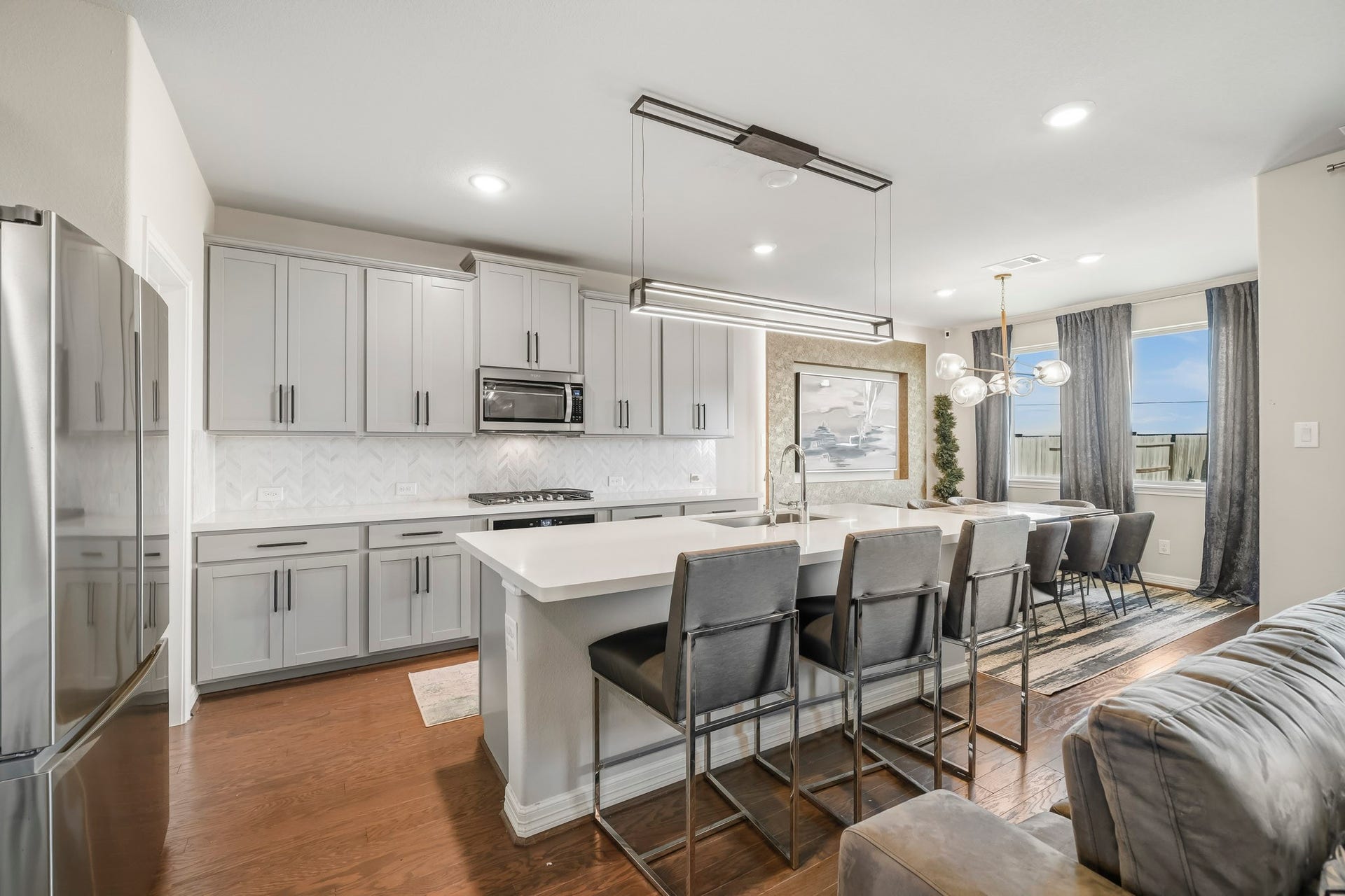 The expansive kitchen island provides generous seating and overlooks the main living space, while large windows bring natural light throughout the shared areas.
