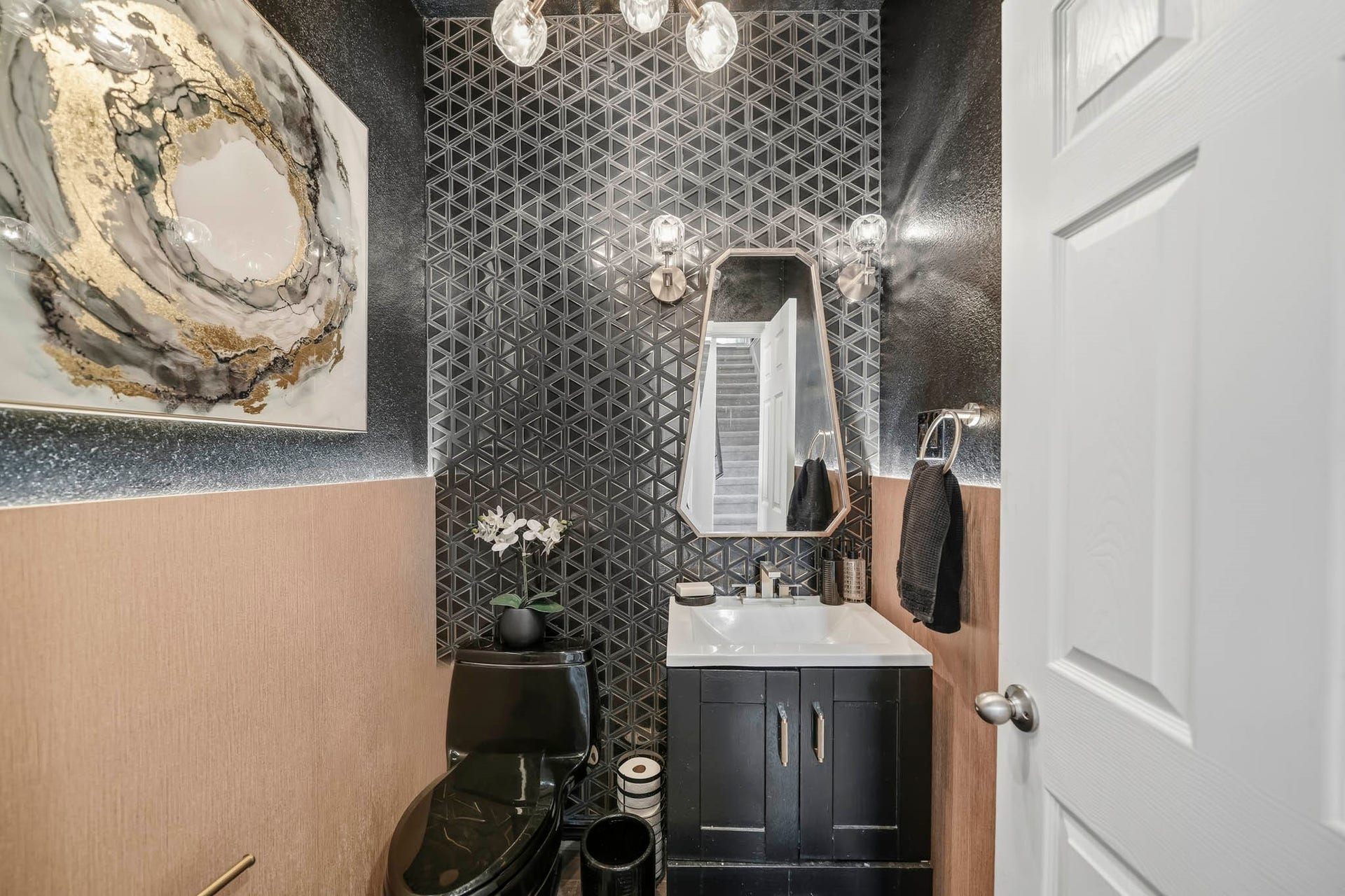 This stylish powder bath makes a bold statement with dramatic geometric tile, rich contrasting finishes, and warm textured wall accents. A sleek vanity, contemporary mirror, and decorative lighting add modern sophistication, while the compact layout maximizes functionality and creates a memorable guest bath.