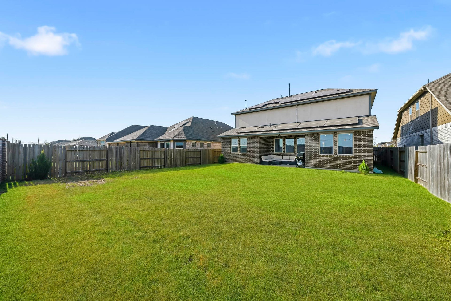 This expansive, fully fenced backyard offers plenty of open green space for outdoor recreation, entertaining, and everyday enjoyment. A covered patio provides a comfortable spot for relaxing or dining outdoors, while the generous lawn easily accommodates a play area with plenty of additional room to enjoy.