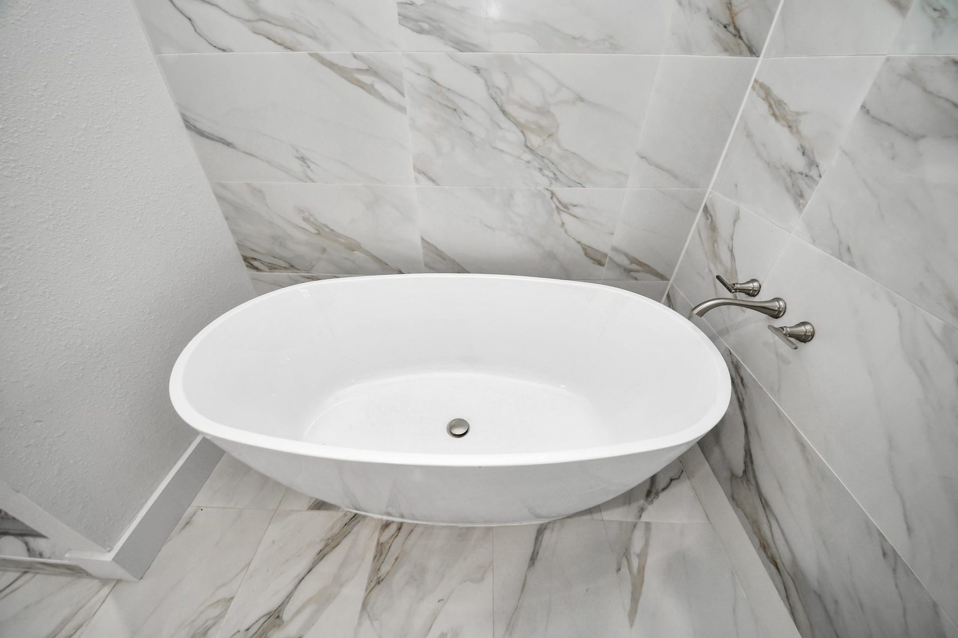 Luxurious freestanding bathtub set against elegant marble tiles, perfect for a relaxing soak.