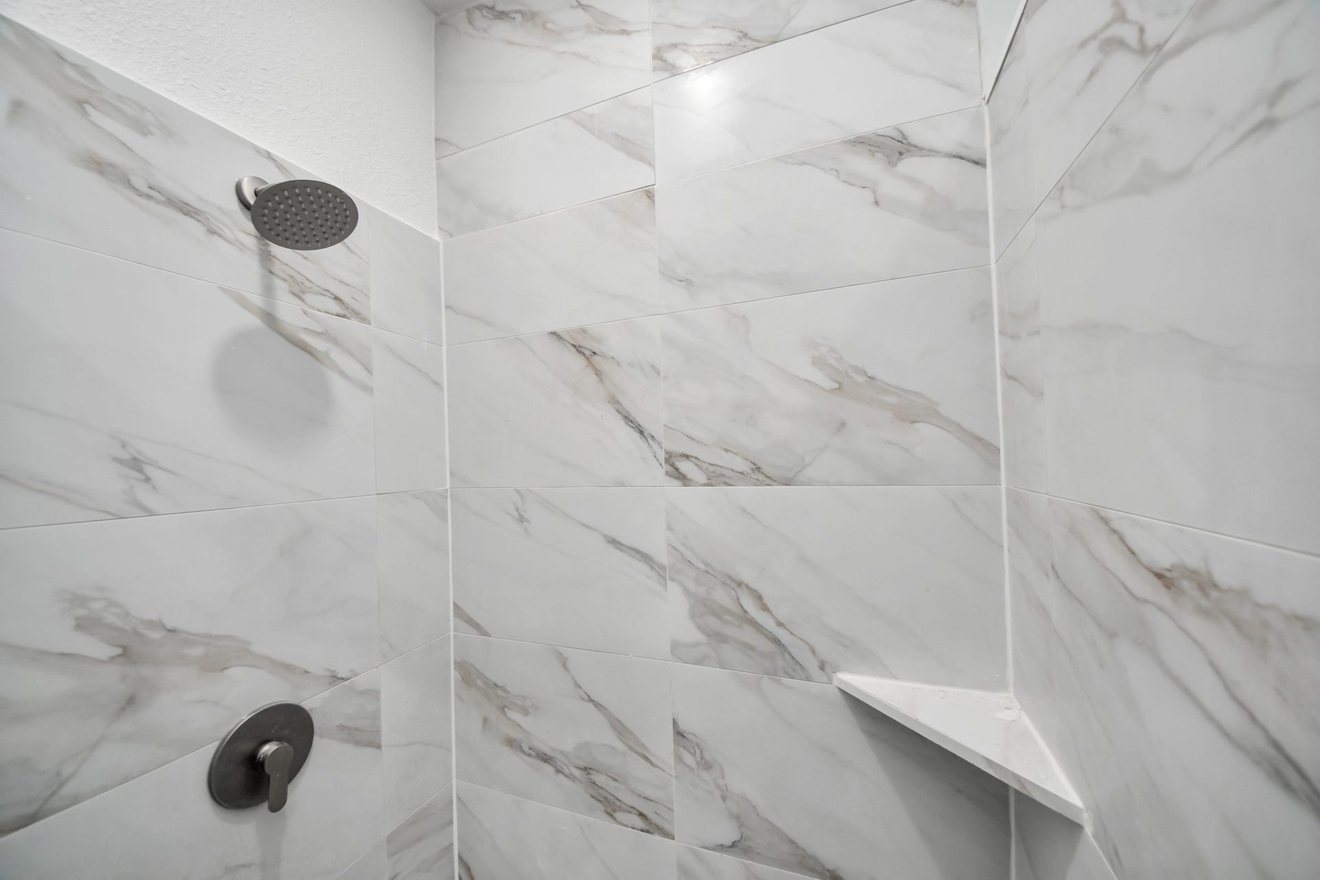Elegant shower featuring luxurious marble tiles and a sleek, modern showerhead.