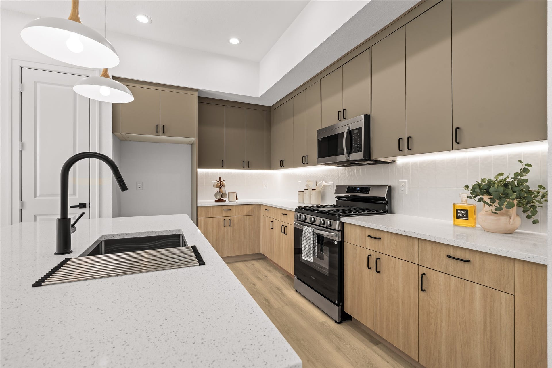 3012 & 3014 Beulah St, Houston, TX 77004 The two-tone cabinets provide plenty of storage space without cluttering the room. Matte black hardware accents the natural wood lower drawers and muted taupe upper cabinets, while under-cabinet LED lighting brightens up the white vertical tile backsplash.