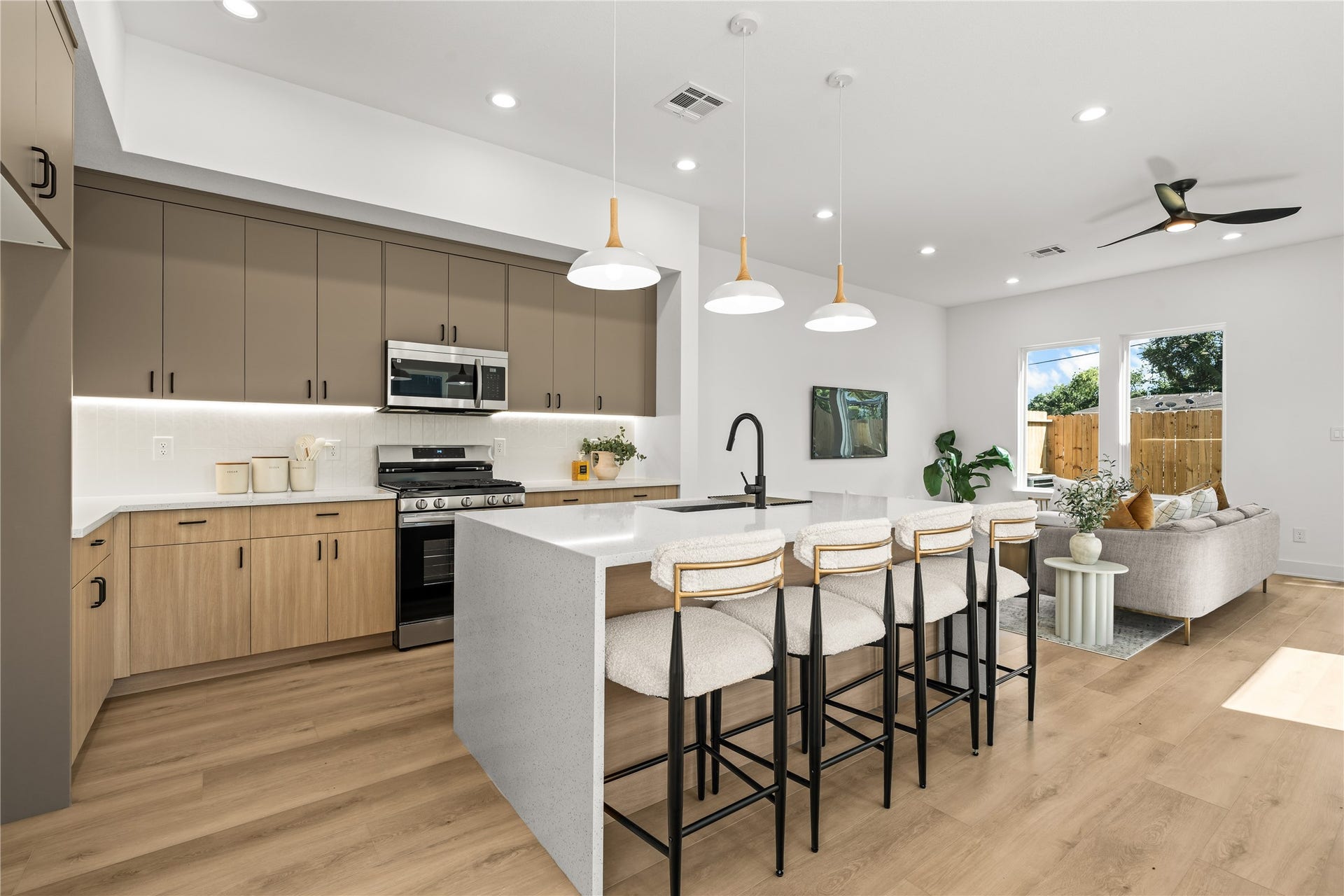 3012 & 3014 Beulah St, Houston, TX 77004 This setup includes a premium stainless steel appliance package with a gas range and built-in microwave, all set against a clean white vertical tile backsplash. The kitchen opens up directly to the living room, keeping the whole space connected while you cook.