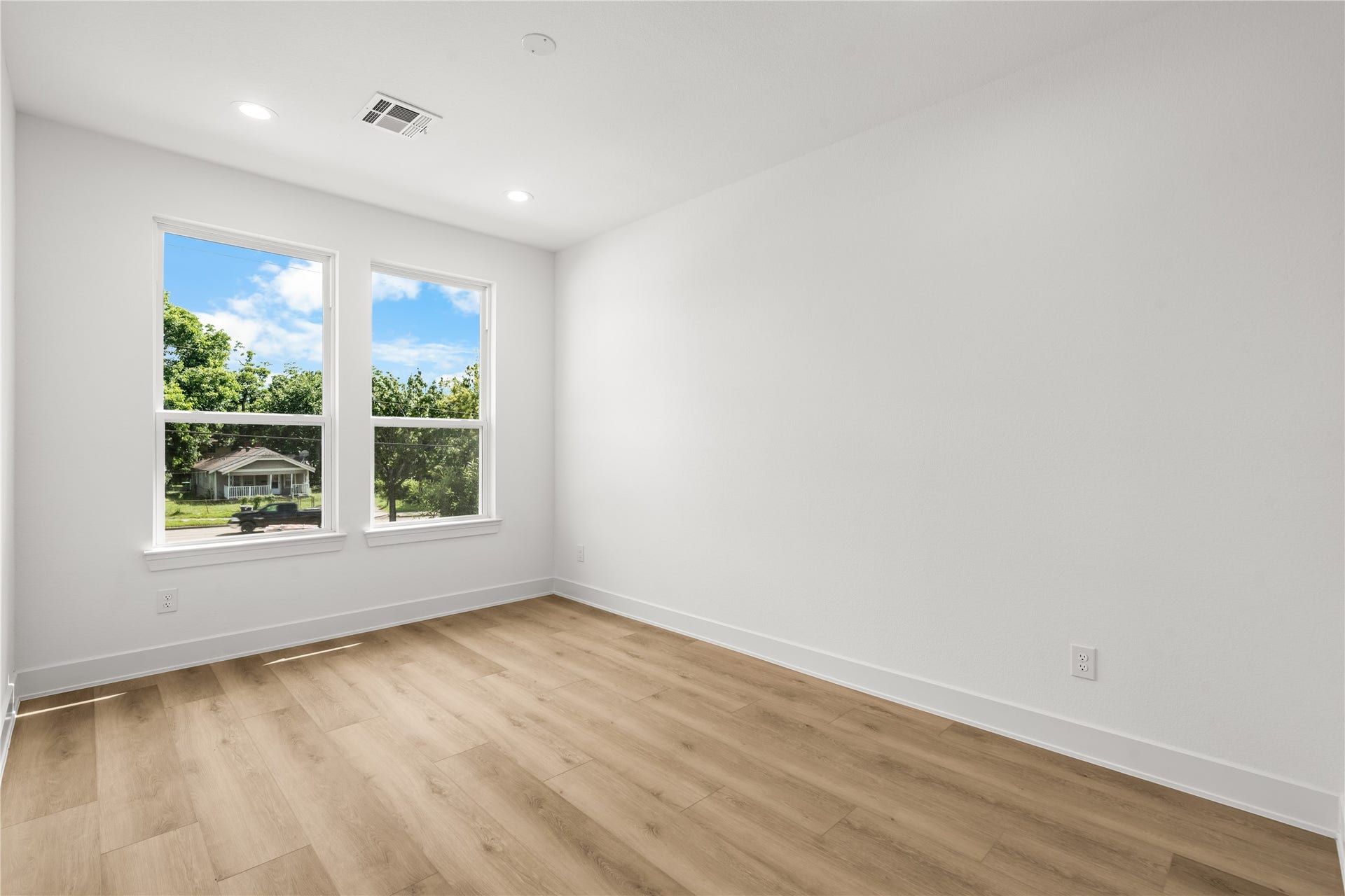 3012 & 3014 Beulah St, Houston, TX 77004 The third bedroom features LVP flooring, smooth white walls, and two large windows with views of mature trees and greenery. The bright, peaceful layout works perfectly as either a bedroom or a home office.