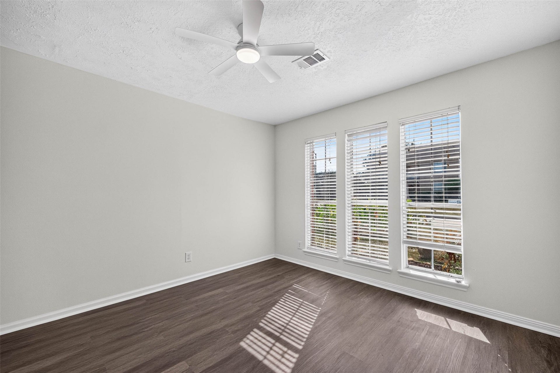 1123 Woodhorn Drive, Houston, TX 77062 Bedroom with wood-look flooring and three tall windows with blinds, brightened by a ceiling fan with light.