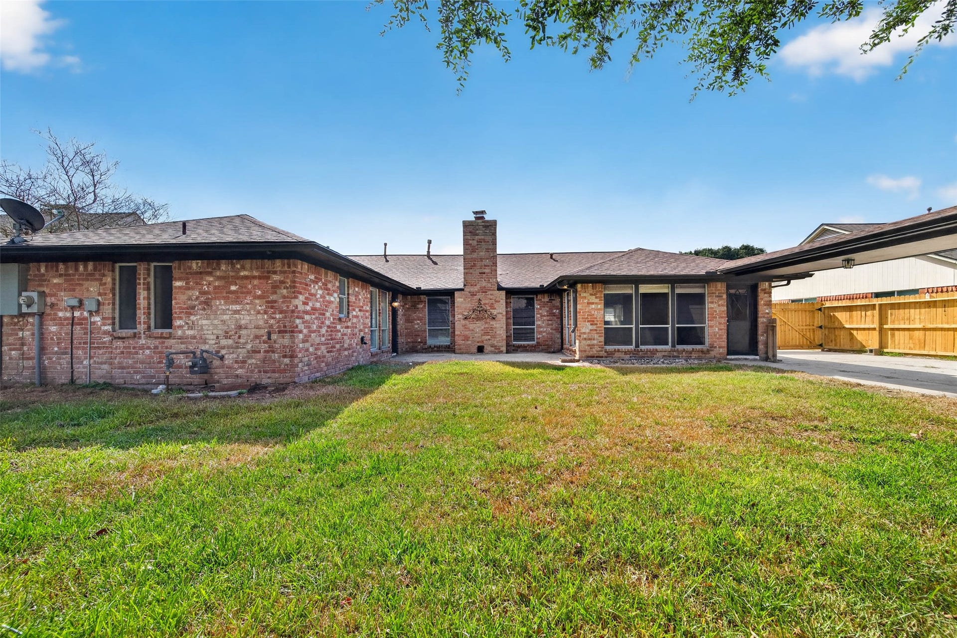 1123 Woodhorn Drive, Houston, TX 77062 Backyard view across the lawn to the brick rear of the home, with the chimney, and large windows.