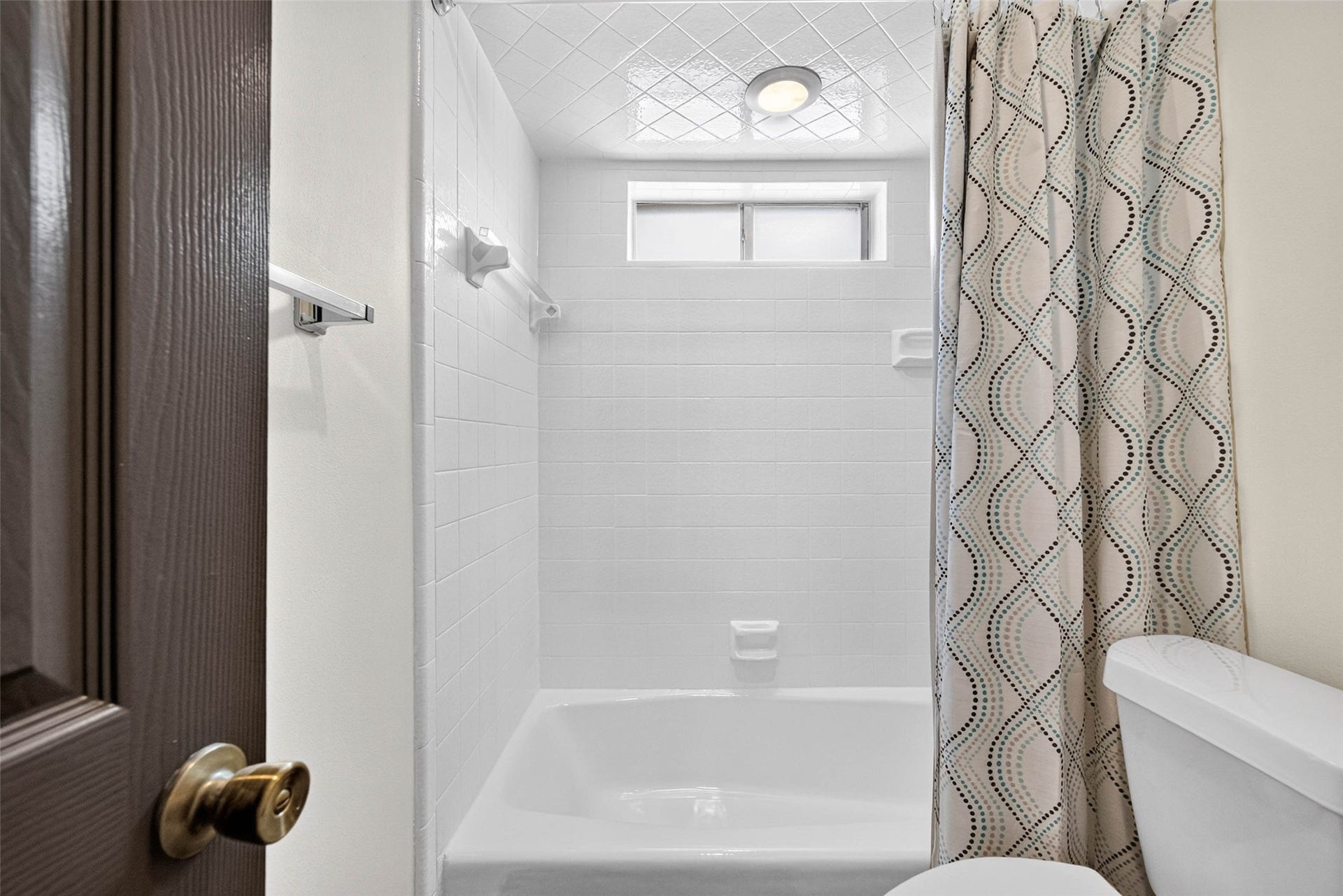 1123 Woodhorn Drive, Houston, TX 77062 Bathroom tub and shower with a subway tile surround, a high window, and a deep tub.