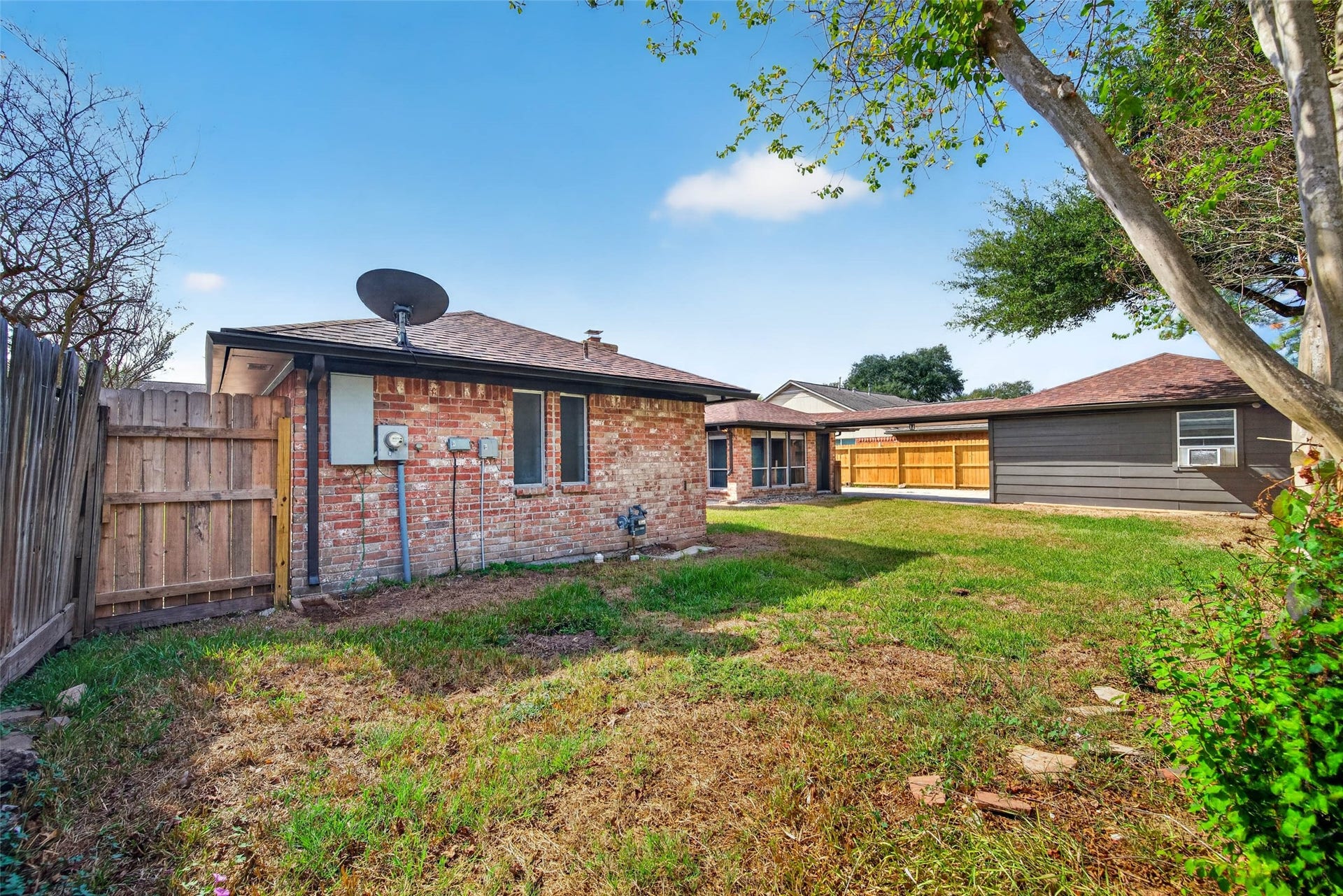 1123 Woodhorn Drive, Houston, TX 77062 Side yard view with the brick side of the home, wooden fencing, and lawn.