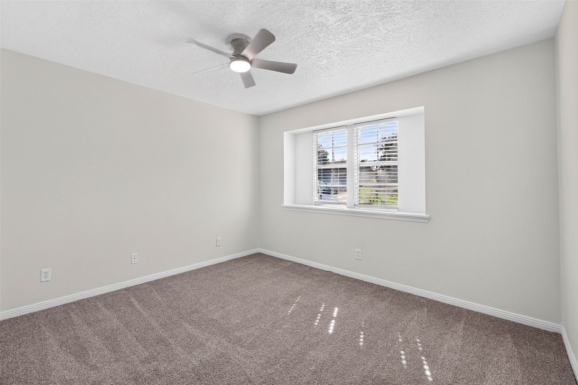 1123 Woodhorn Drive, Houston, TX 77062 Carpeted bedroom with two windows set in a recessed niche, a ceiling fan with light, and sunlight falling across the carpet.