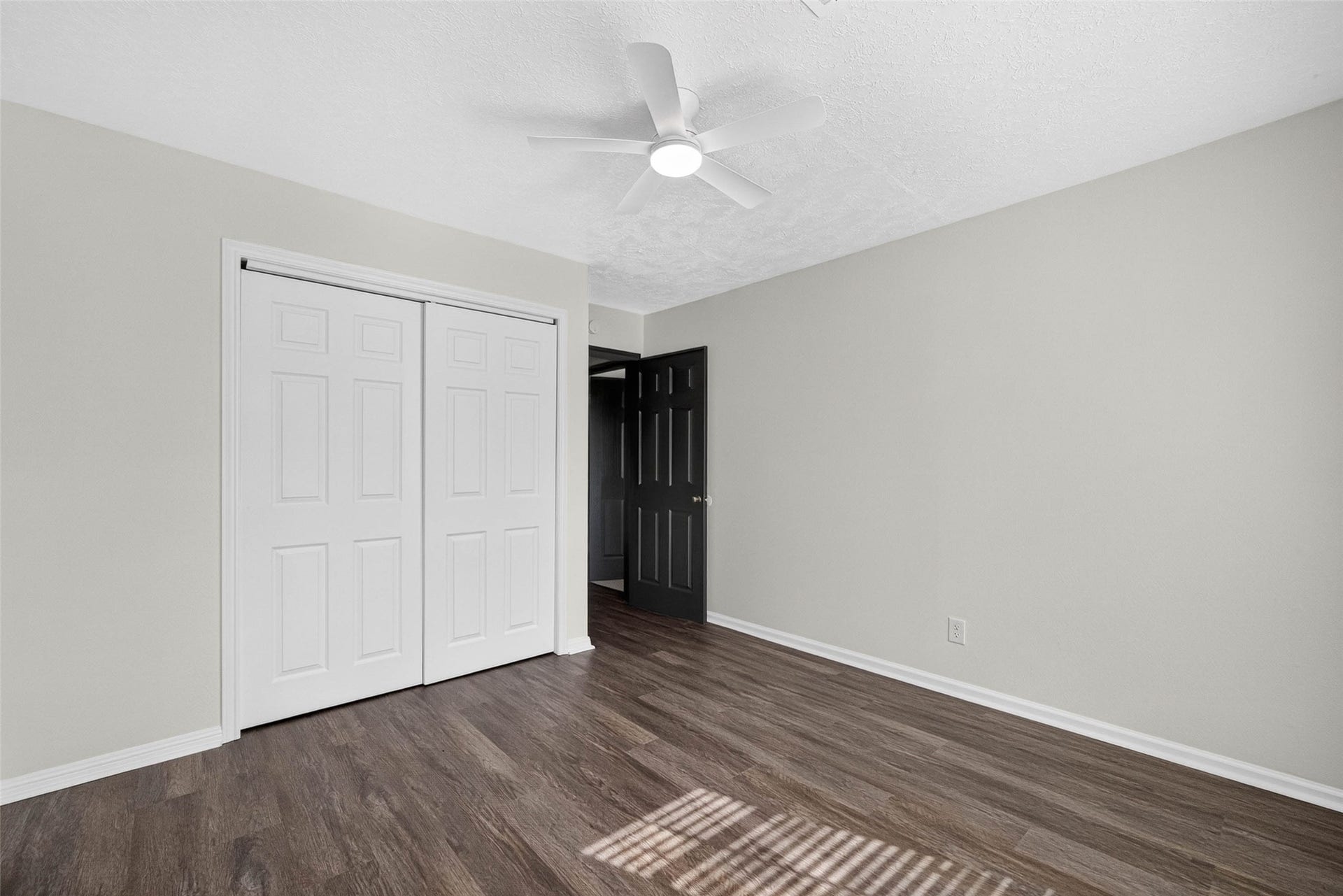 1123 Woodhorn Drive, Houston, TX 77062 Bedroom with wood-look flooring, sliding closet doors, a dark interior door, and sunlight striping the floor through blinds.