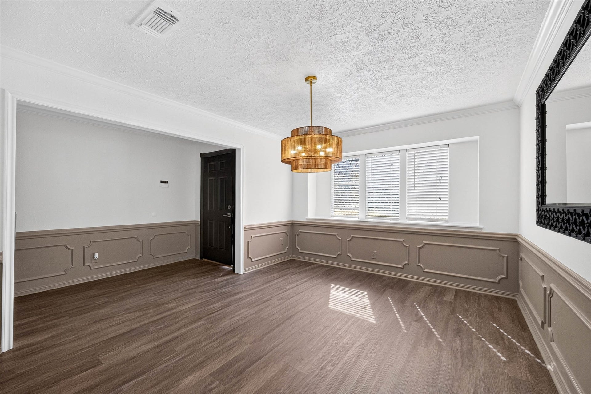 1123 Woodhorn Drive, Houston, TX 77062 Front room with two-tone walls and raised-panel wainscoting, wood-look flooring, a tiered pendant light, and three windows with blinds.