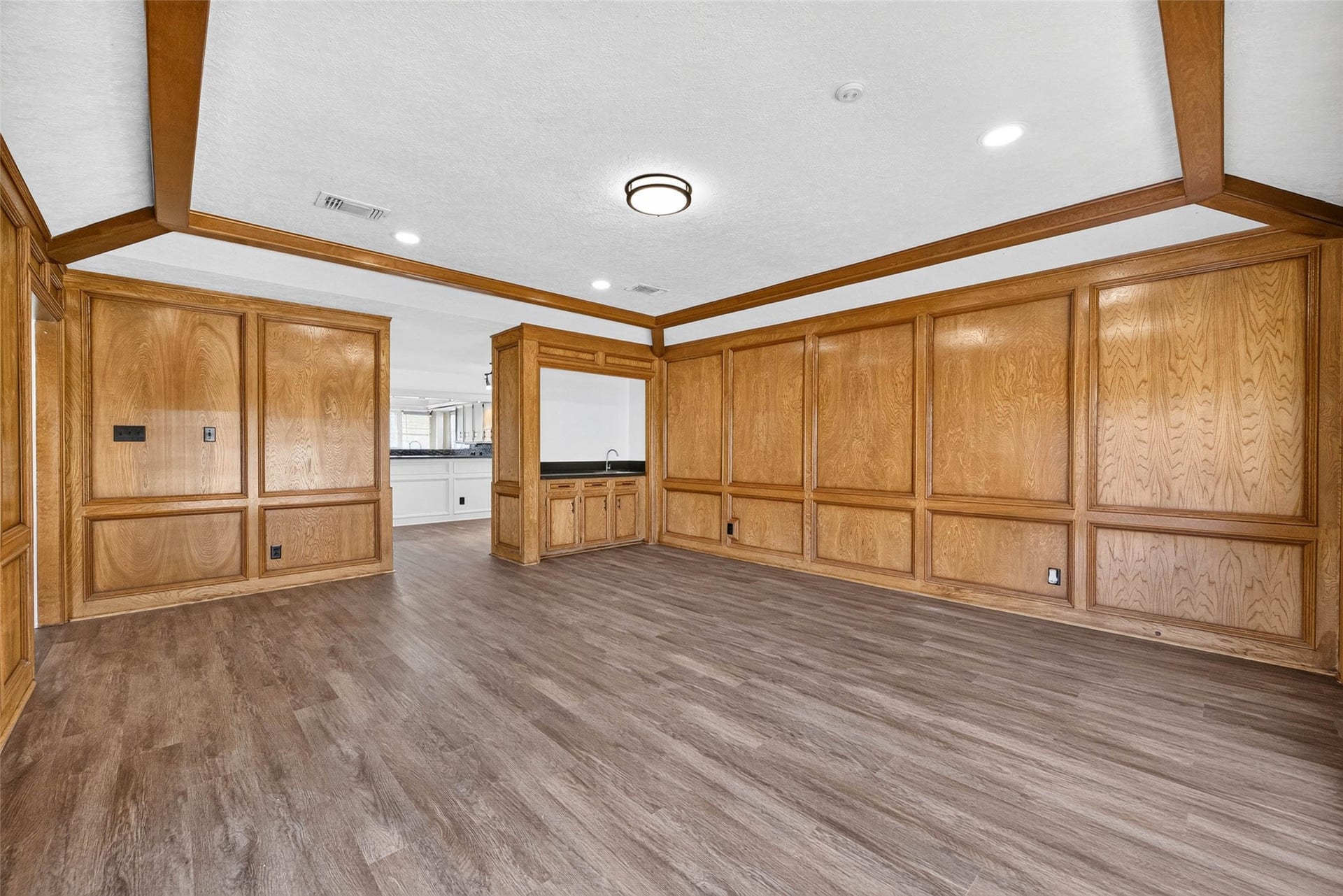 1123 Woodhorn Drive, Houston, TX 77062 nother angle of the paneled living room, where the wood beams and wood-look floors carry through to a bar nook and the kitchen beyond.