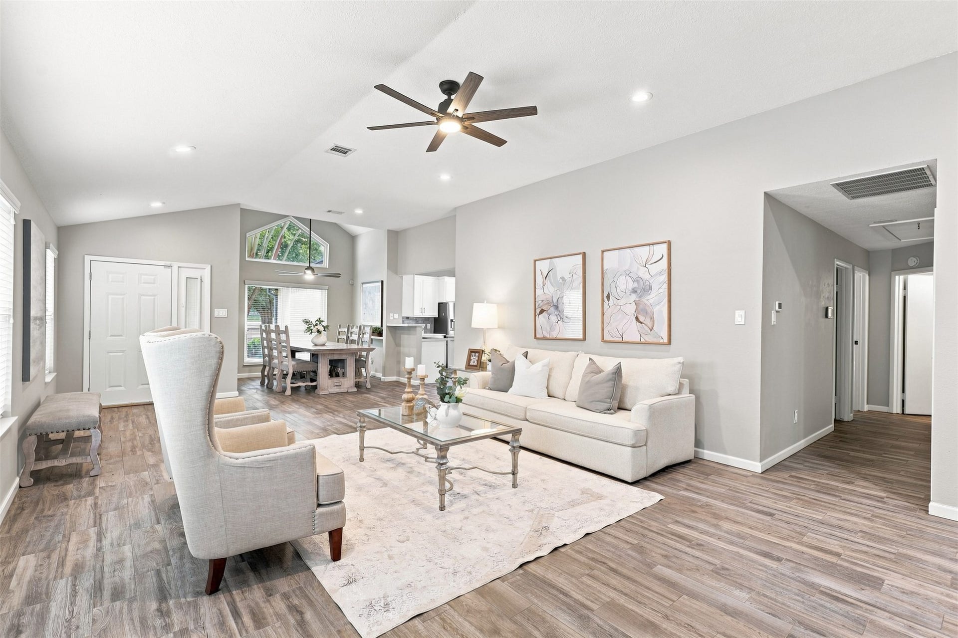 Open-concept living and dining areas feature vaulted ceilings, wood flooring, and a seamless layout with easy access to the kitchen and bedroom hallway.