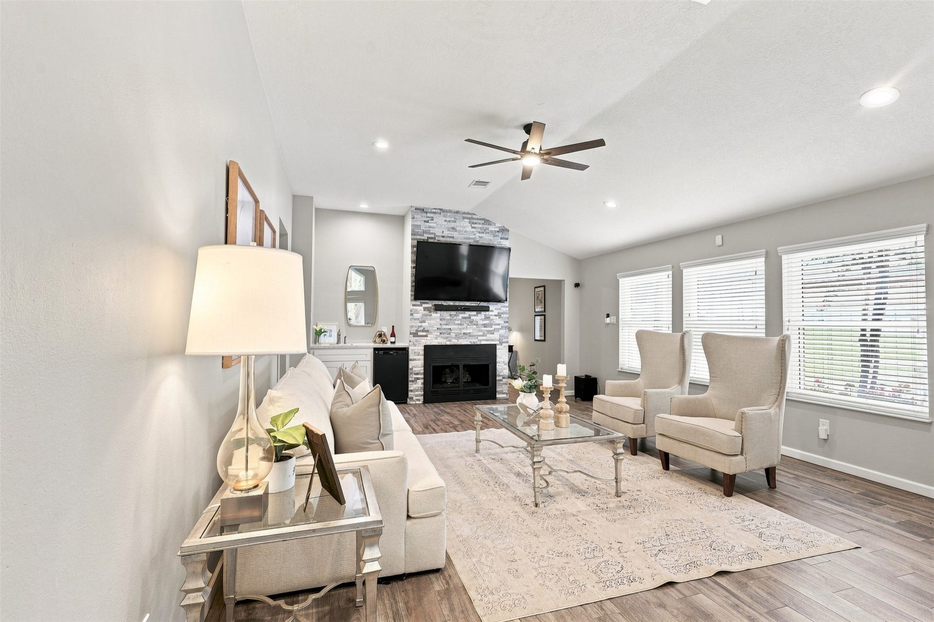 Inviting living room centered around a floor-to-ceiling fireplace, with vaulted ceilings, recessed lighting, and a wall of windows filling the space with natural light.