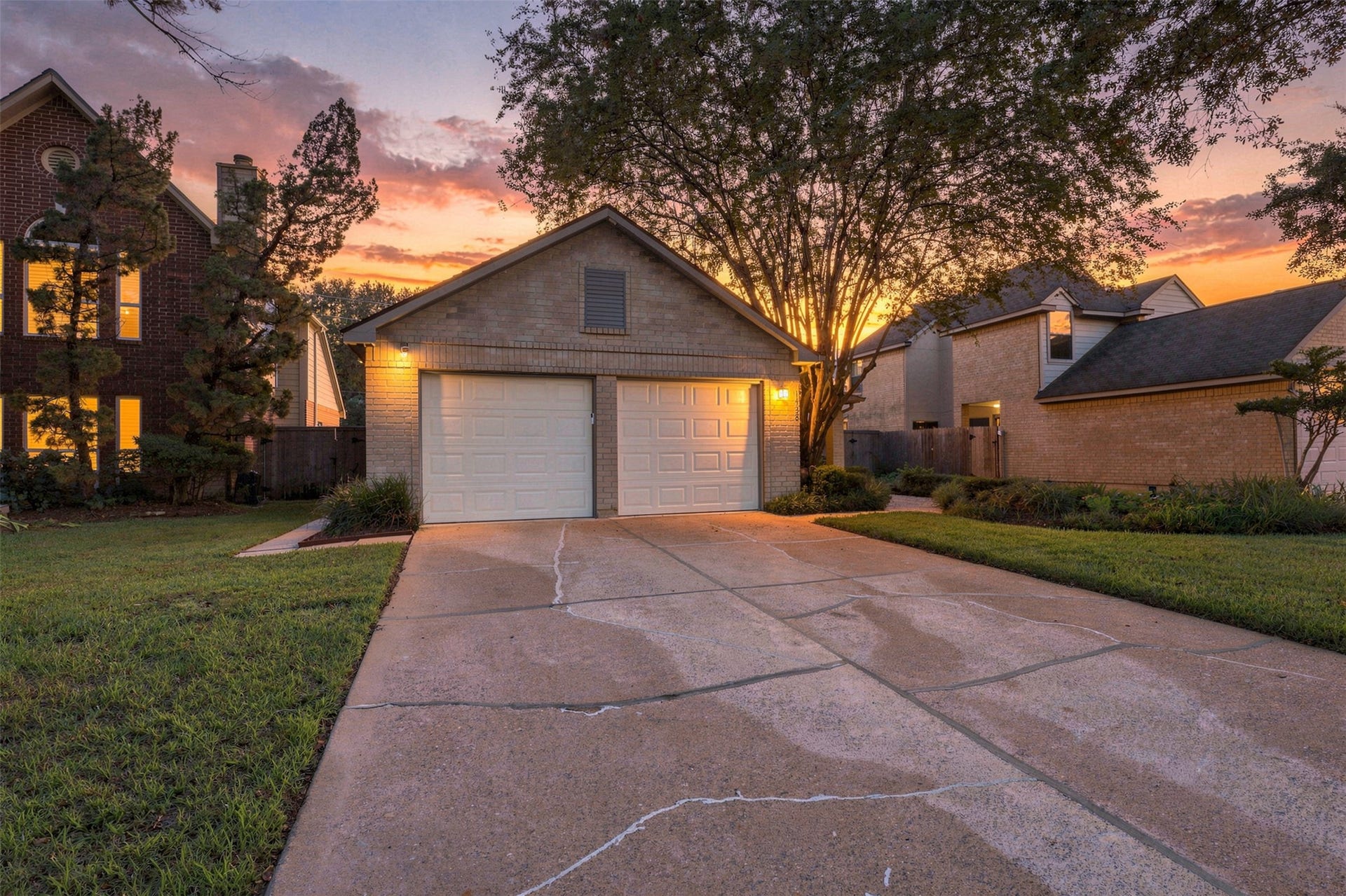 Beautiful curb appeal featuring a two-car garage, mature shade trees, and well-maintained landscaping.
