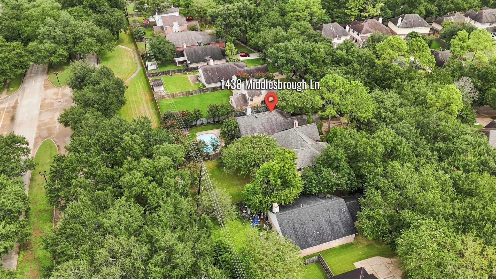 Elevated aerial view highlights the homes location among mature trees, with the backyard pool and surrounding neighborhood visible.