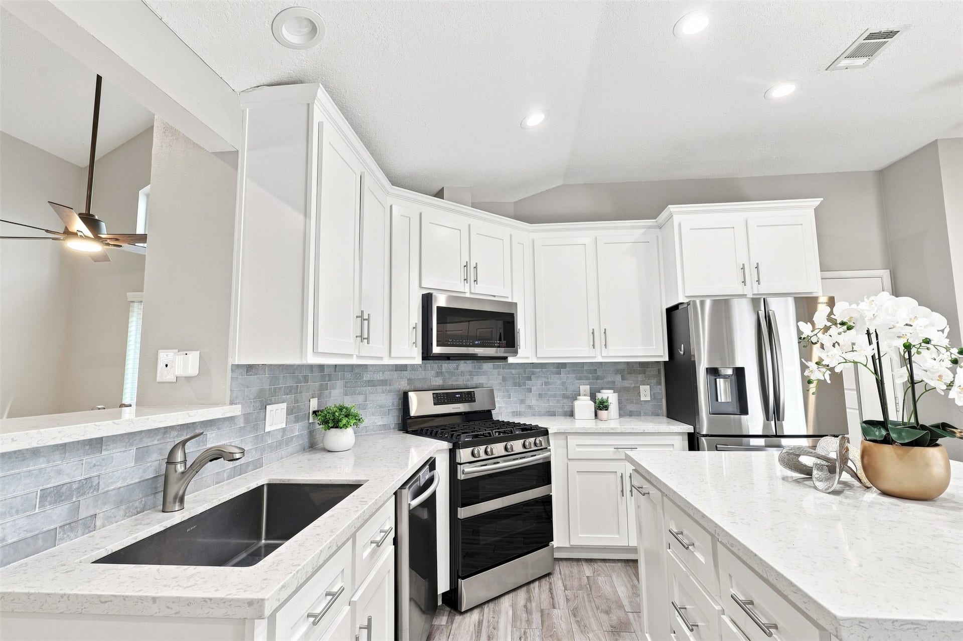 Well-appointed kitchen offers generous counter space, abundant white cabinetry, stainless steel appliances, a gas range, and coordinating tile backsplash.