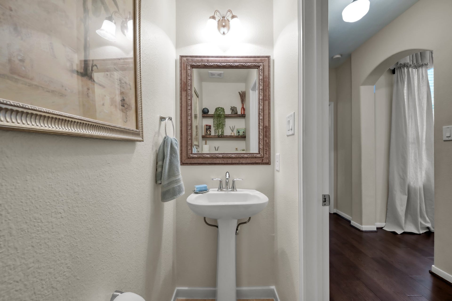 2502 Wynden Meadow Lane, Conroe, TX 77304 Charming guest powder bath with pedestal sink, decorative mirror, and a warm, inviting feel for visitors.