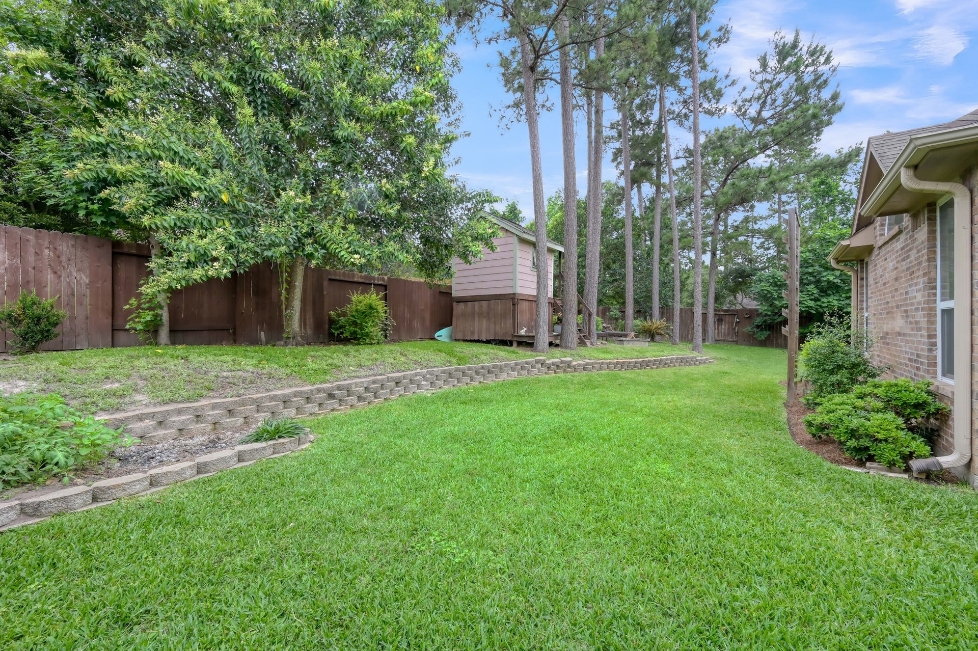 2502 Wynden Meadow Lane, Conroe, TX 77304 Large backyard with tiered landscaping, towering pine trees, and endless possibilities for outdoor living, gardening, or family gatherings.