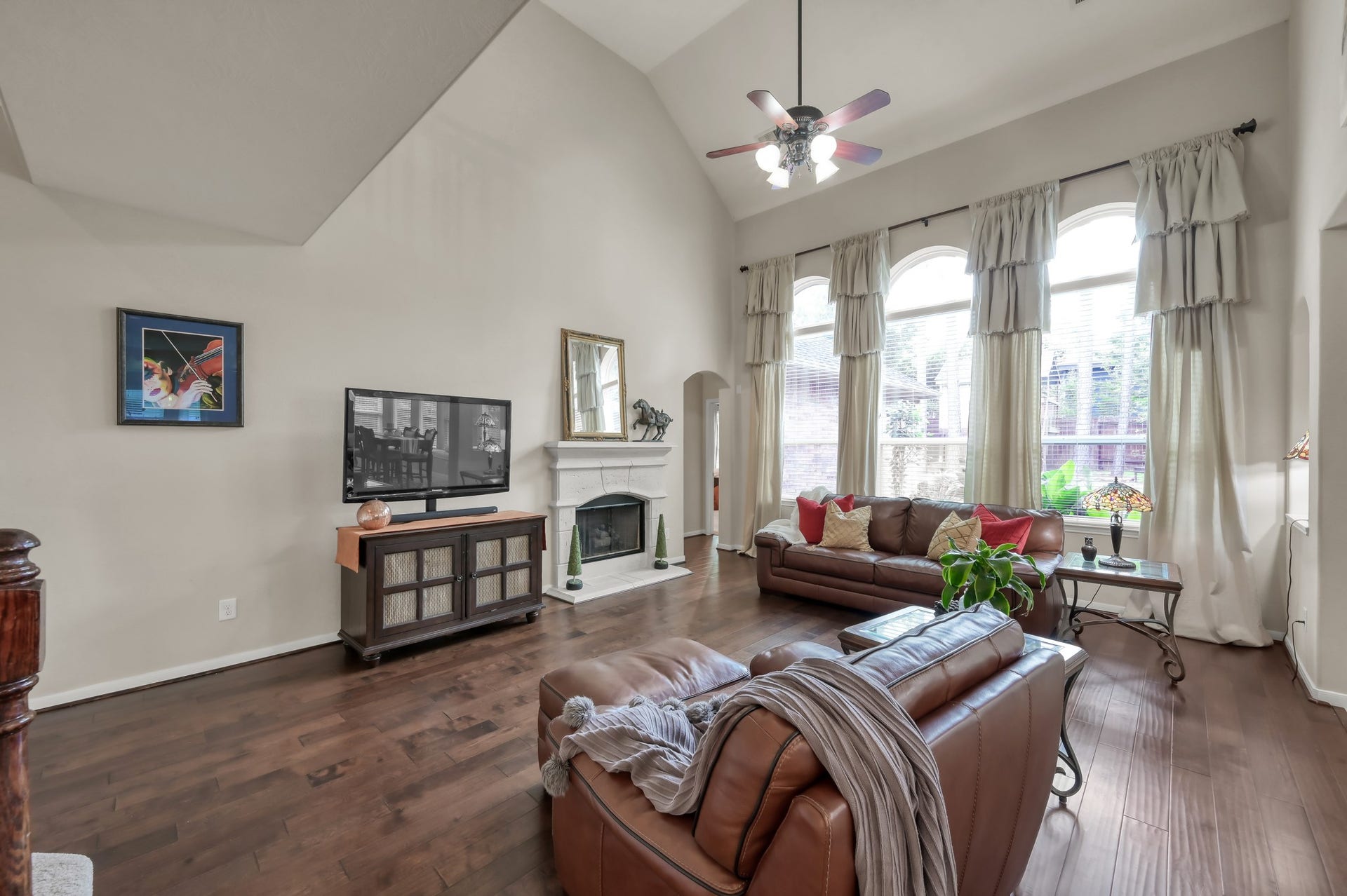 2502 Wynden Meadow Lane, Conroe, TX 77304 Tall windows and high ceilings make this living room feel incredibly spacious and airy. A beautiful focal-point fireplace and rich wood flooring add warmth and charm to the heart of the home.