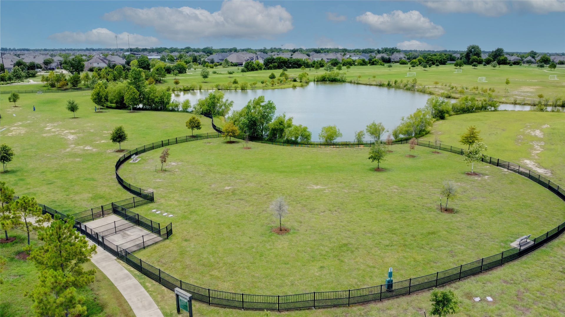 3423 Tranquil Harvest Trail, Richmond, TX 77406 Aerial view of a community lake surrounded by open green space, walking paths, fencing, and nearby homes.