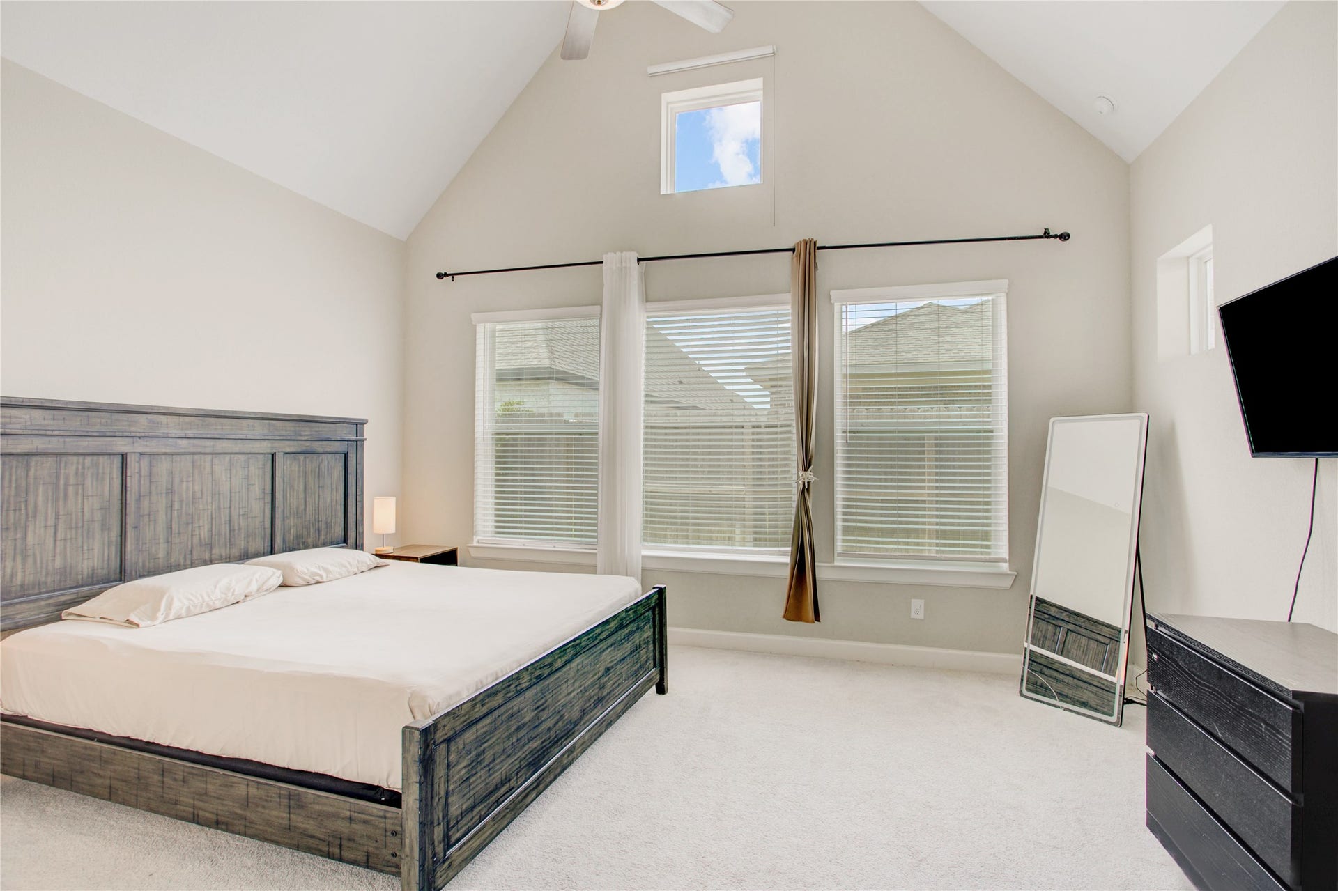 3423 Tranquil Harvest Trail, Richmond, TX 77406 Primary bedroom featuring a vaulted ceiling, wall of windows and upper-level window.