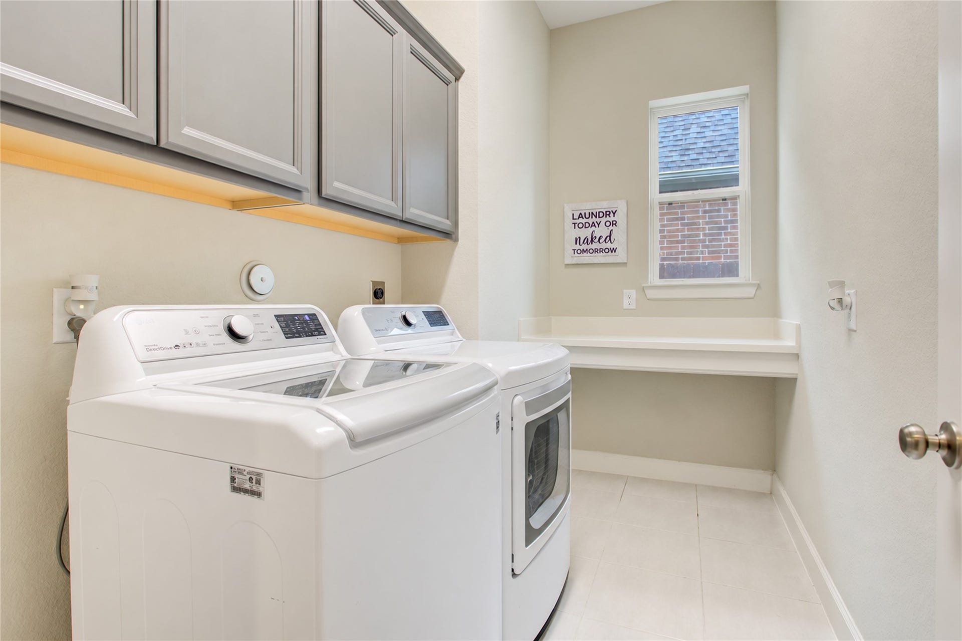 3423 Tranquil Harvest Trail, Richmond, TX 77406 Laundry room featuring a washer and dryer, overhead cabinetry, built-in shelving, and a window.
