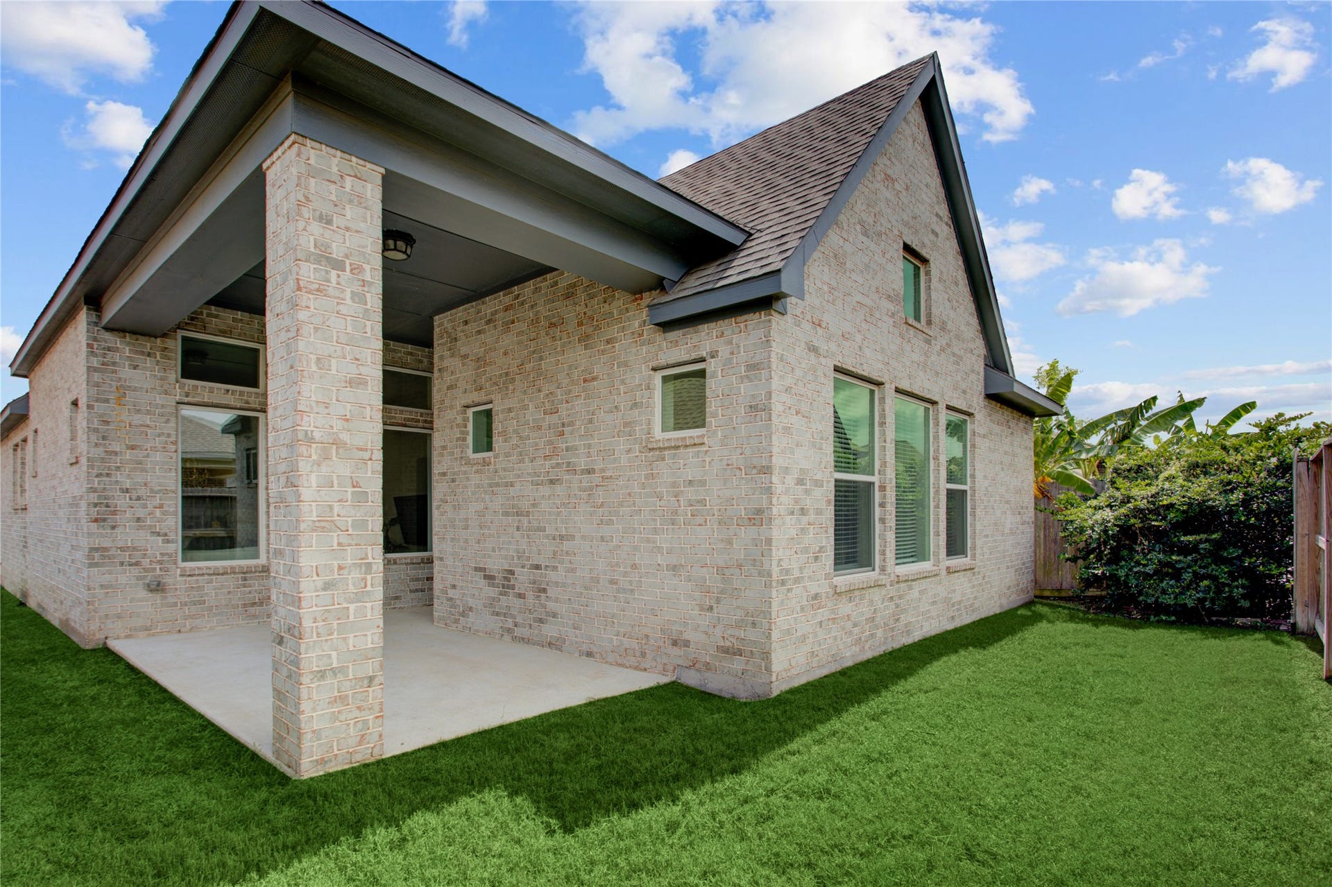 3423 Tranquil Harvest Trail, Richmond, TX 77406 Spacious backyard showcasing the homes brick exterior, covered patio, green lawn, fenced yard.