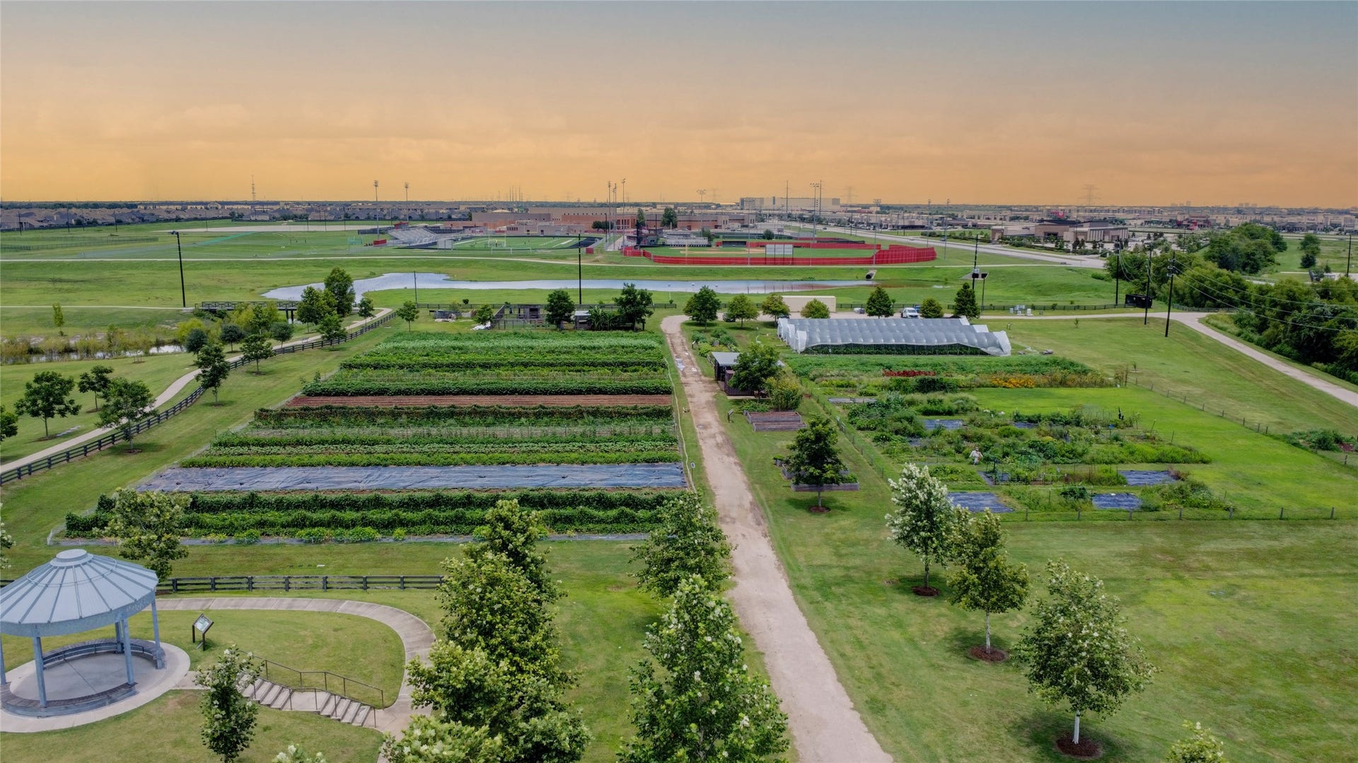 3423 Tranquil Harvest Trail, Richmond, TX 77406 Aerial view of the community showing landscaped grounds, garden plots, walking paths, a gazebo, and nearby athletic fields.