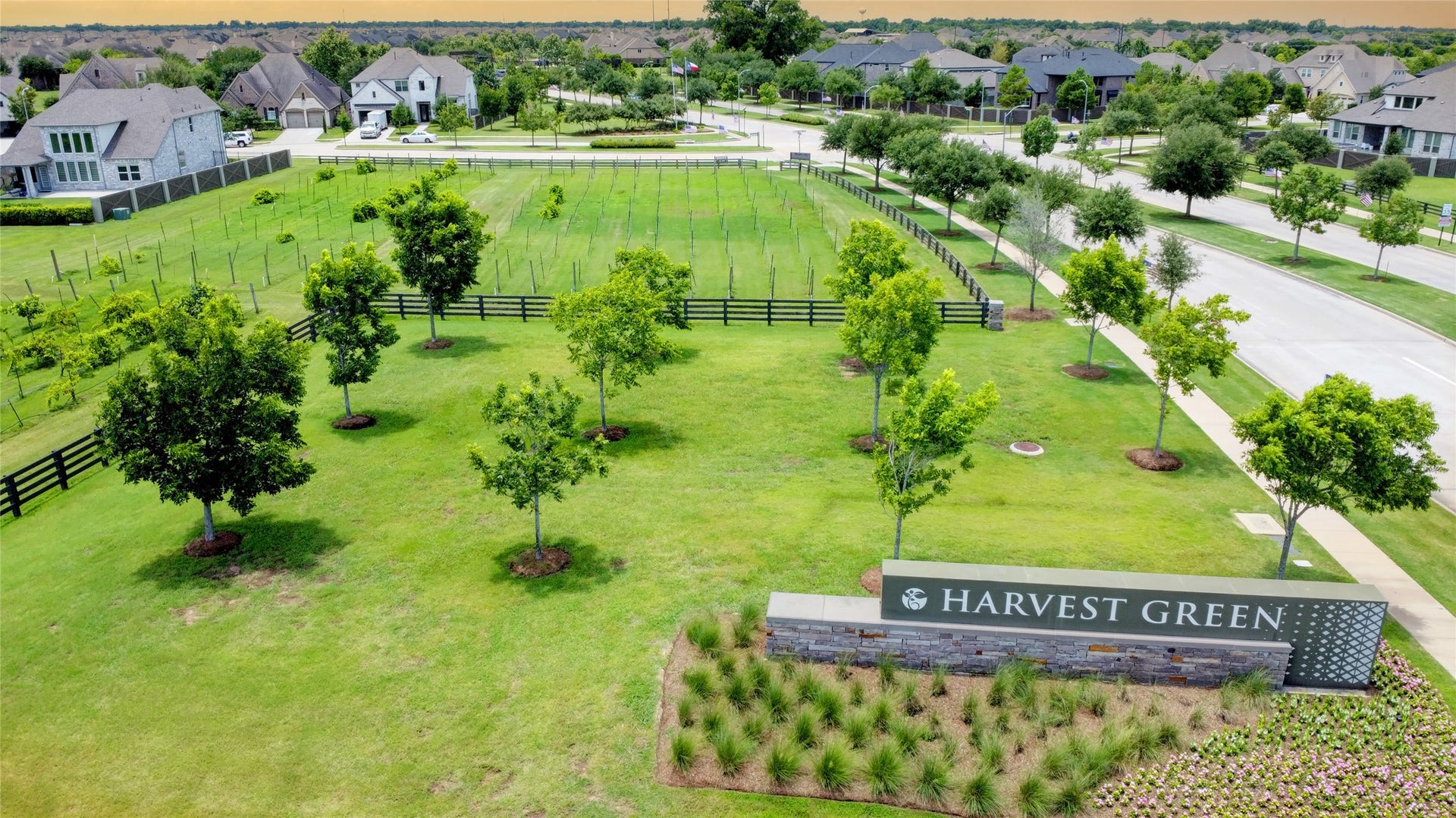 3423 Tranquil Harvest Trail, Richmond, TX 77406 Aerial view of the Harvest Green community, featuring landscaped green space, tree-lined streets, surrounding homes, and the Harvest Green entrance sign.
