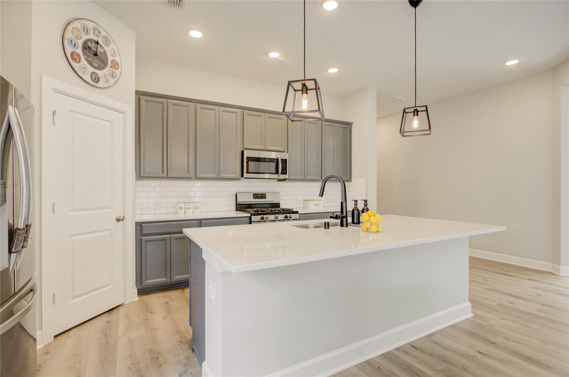 3423 Tranquil Harvest Trail, Richmond, TX 77406 Elegant kitchen showcasing gray cabinetry, quartz countertops, a spacious island with an undermount sink and, subway tile backsplash.
