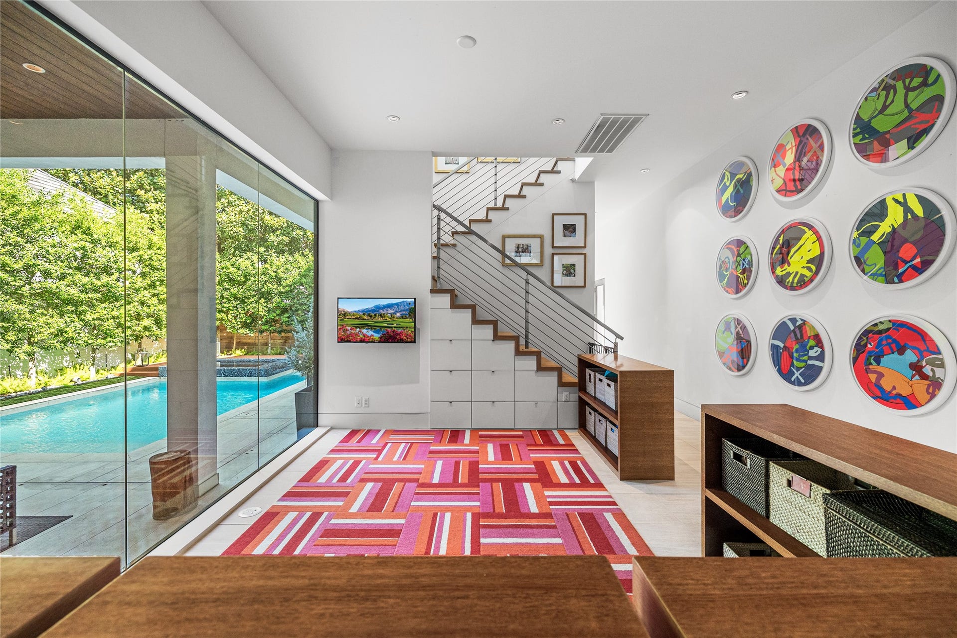 2608 Barbara Lane, Houston, TX 77005 Wrapped in floor-to-ceiling glass overlooking the pool and summer kitchen, this flex space offers ample storage, including drawers built beneath the stairs. Now a playroom, it could just as easily become a reading area or a quiet retreat.