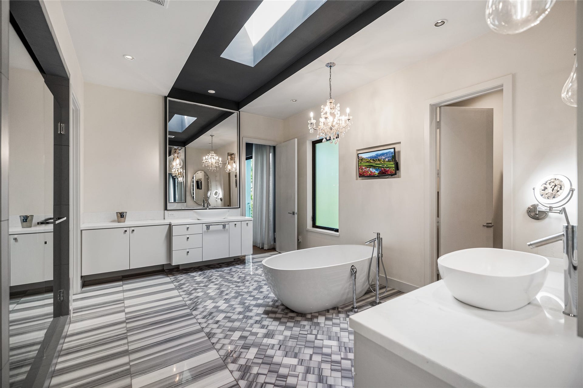 2608 Barbara Lane, Houston, TX 77005 Daylight from an above skylight, crystal chandelier overhead, and a freestanding soaking tub set on marble. A primary bath of quiet indulgence. The bedroom lies just beyond, and a private water closet is tucked away to the right.