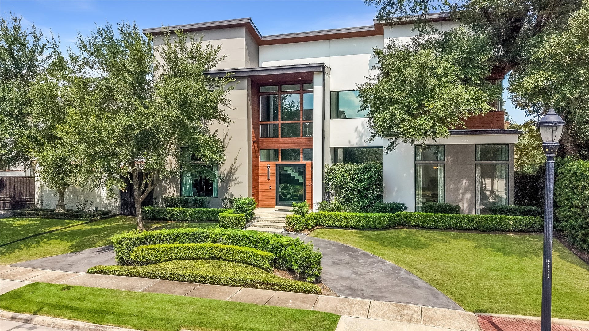 2608 Barbara Lane, Houston, TX 77005 Day time picture of the stunning facade. Step up through manicured hedges to warm wood, open glass, and a gentle rise of steps to a welcoming pivot door that welcomes you home.