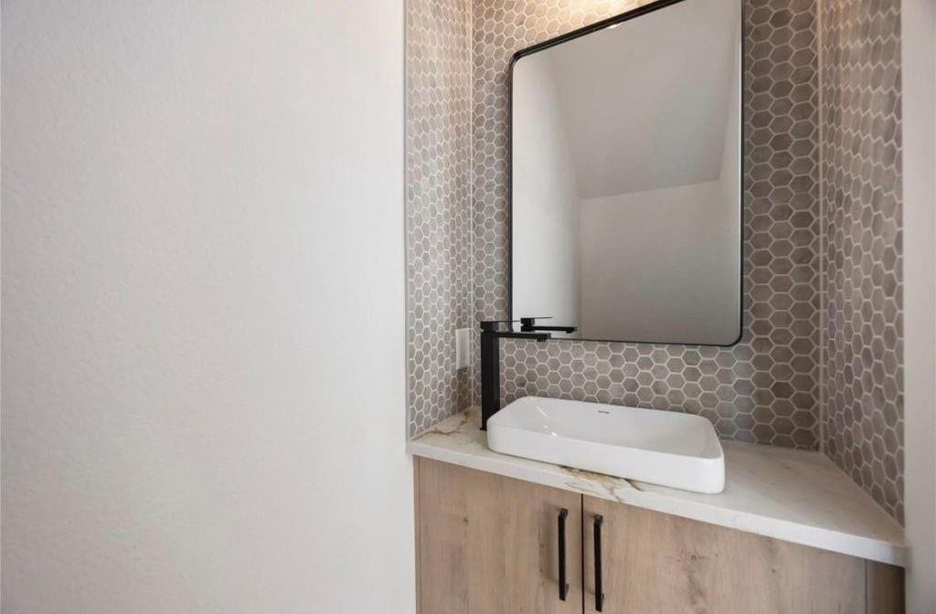 7920 Boy Street, #B, Houston, TX 77028 Stylish half bathroom featuring a contemporary vanity, decorative mirror, and modern fixtures.