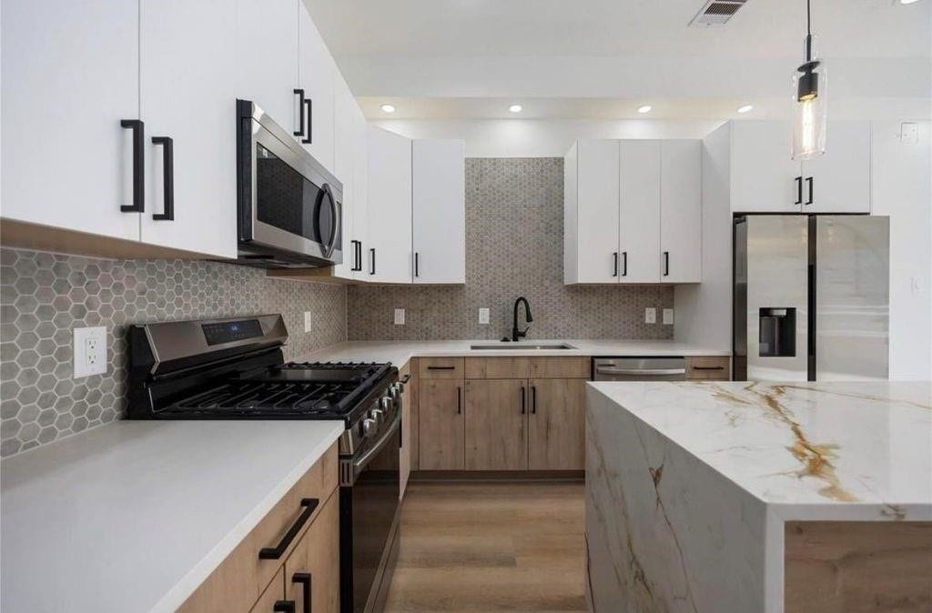 7920 Boy Street, #B, Houston, TX 77028 Modern kitchen featuring a spacious center island, stainless steel appliances, stylish cabinetry, and ample counter space.