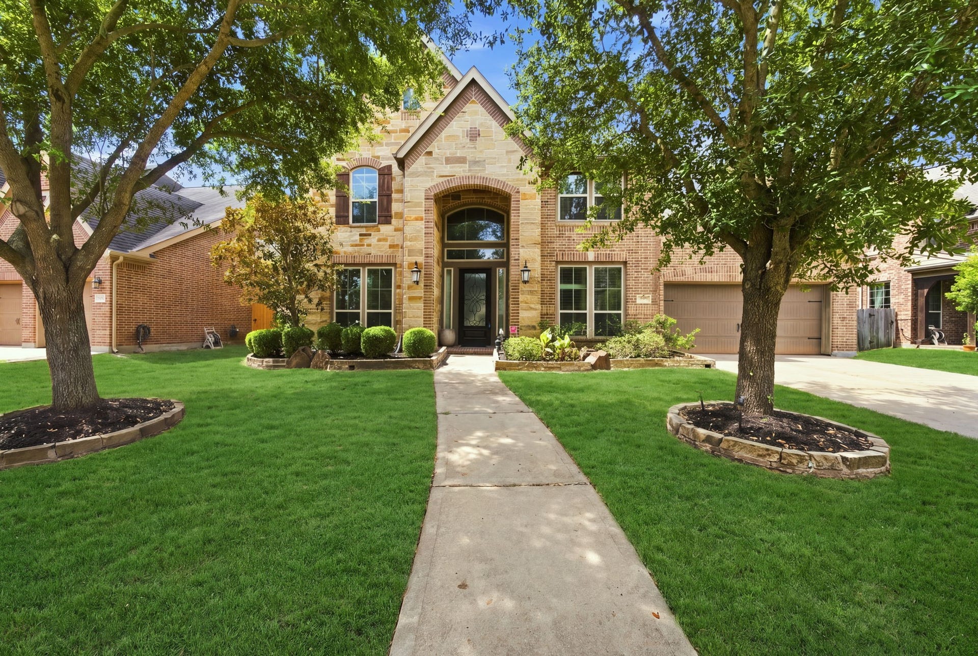 Elegant brick and stone home with a covered entry, and arched front door.