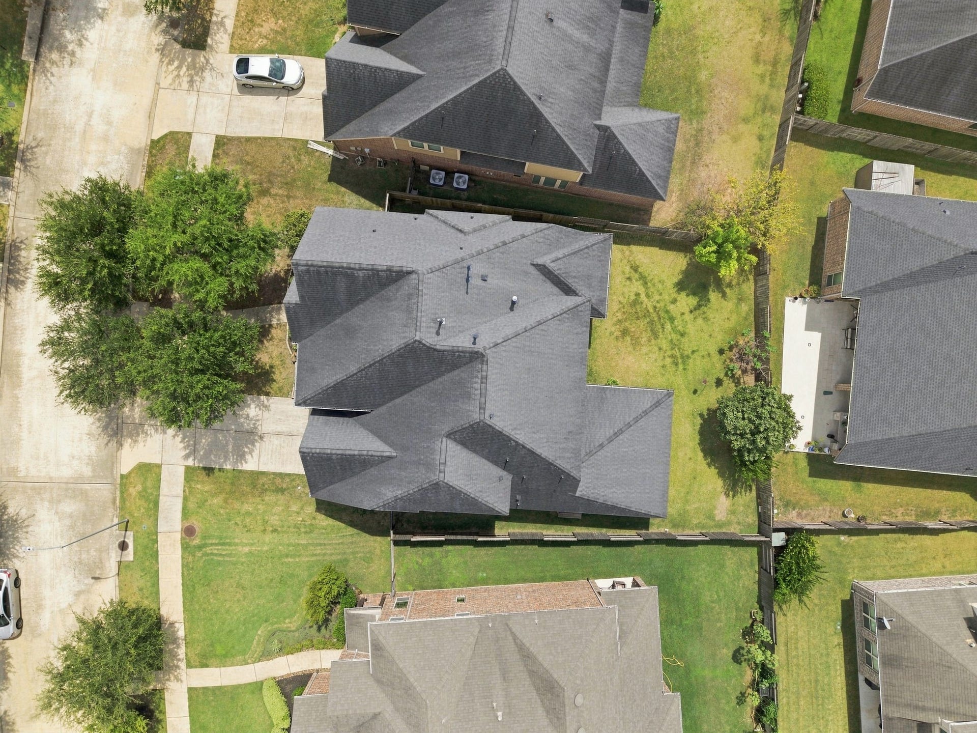 Overhead drone shot showing the home's roofline and footprint within the subdivision.