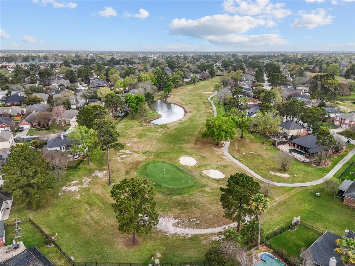 This photo showcases a residential neighborhood adjacent to a golf course, featuring lush greenery, a small pond, and well-maintained homes. Ideal for golf enthusiasts seeking a scenic and serene environment.