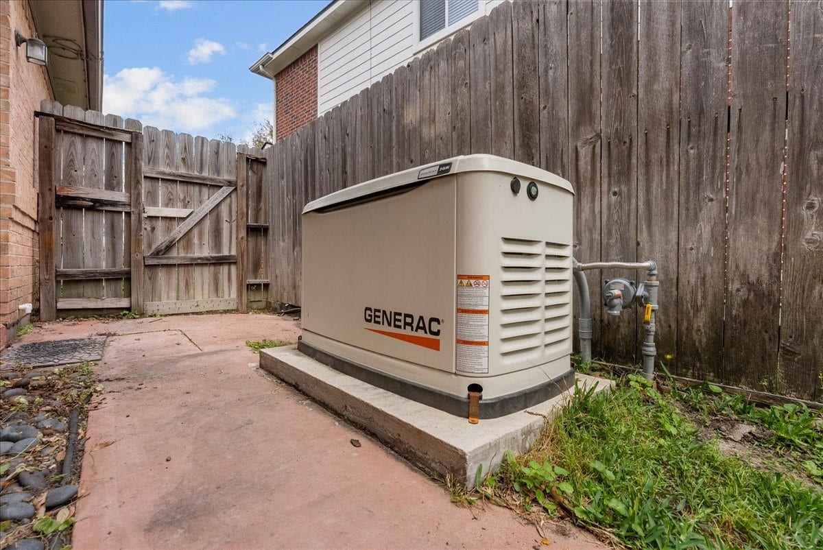 This photo shows a Generac home backup generator installed on a concrete pad in a fenced outdoor area, providing reliable power during outages.