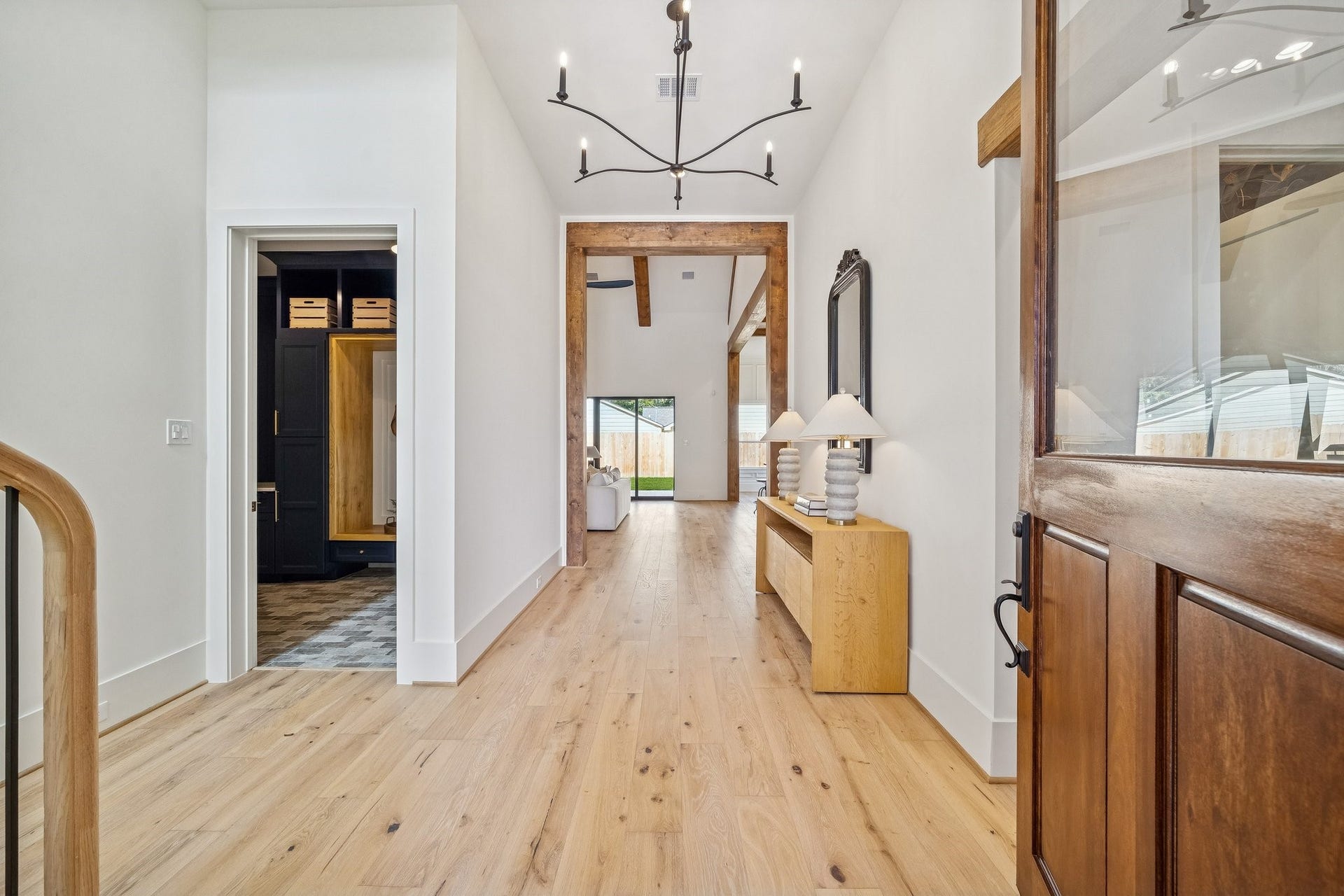 The front door is 9 ft tall and opens to a wide foyer with an elegant chandelier. The mudroom and garage doors are on the left.
