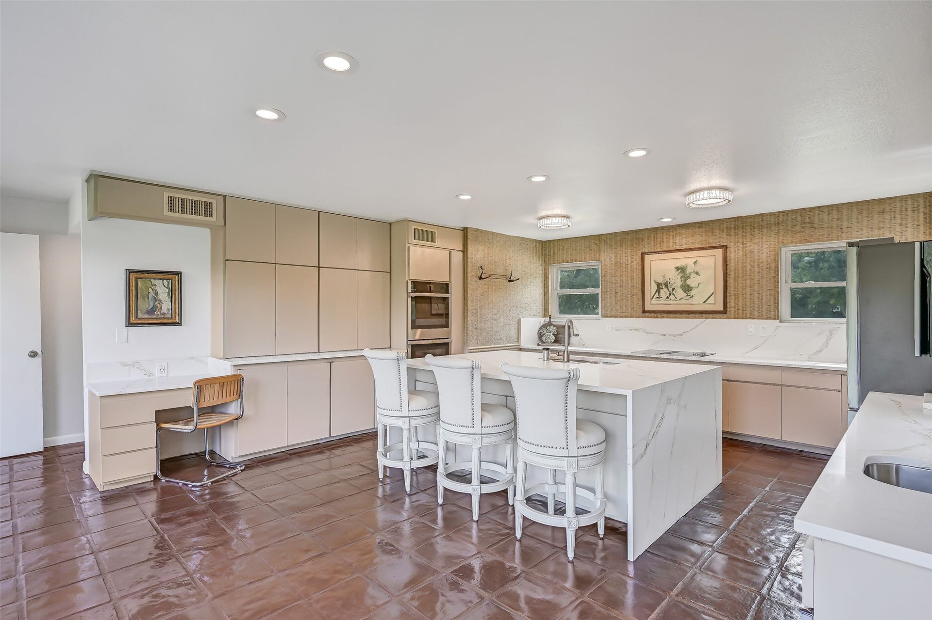 300 Courtlandt Place, Friendswood, TX 77546 The beautifully renovated 17' x 21' kitchen offers an impressive combination of style & functionality, with extensive contemporary cabinetry, quartz countertops, an oversized waterfall island with bar seating & painted tile flooring. A built-in desk area adds convenience.