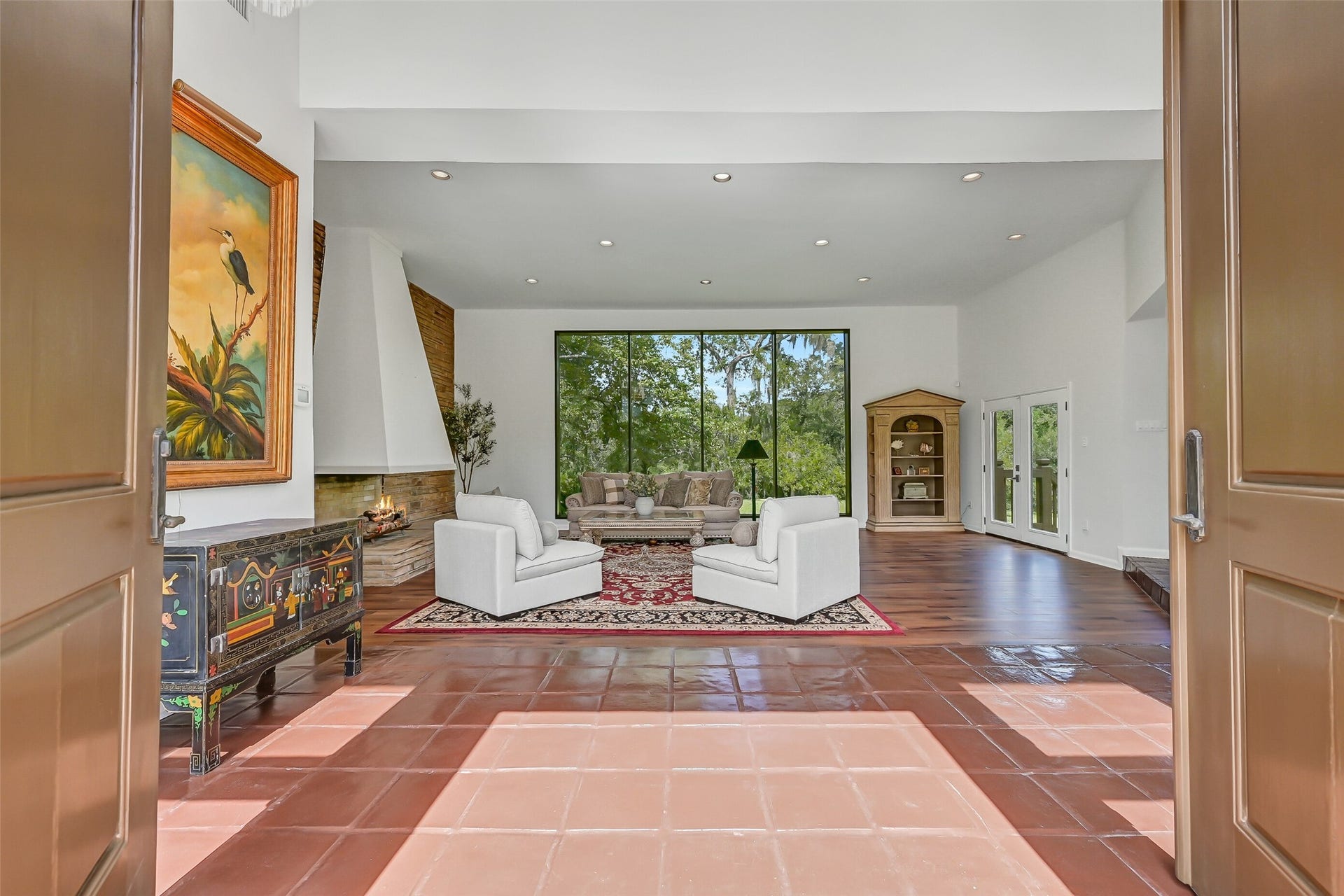 300 Courtlandt Place, Friendswood, TX 77546 Measuring approximately 29' x 27', the expansive sunken living room features 12' ceilings, recessed lighting & a dramatic stone fireplace with sculptural stucco hood and extended stone hearth. Oversized windows frame beautiful views of the surrounding acreage, filling the room with natural light.